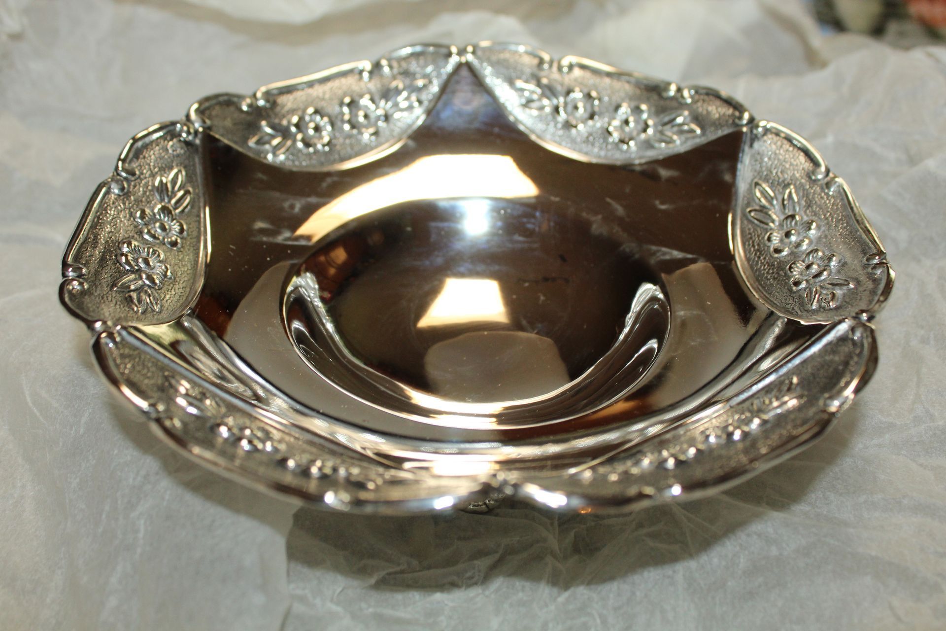 Silver ornate serving dish with scalloped edges and embossed floral details