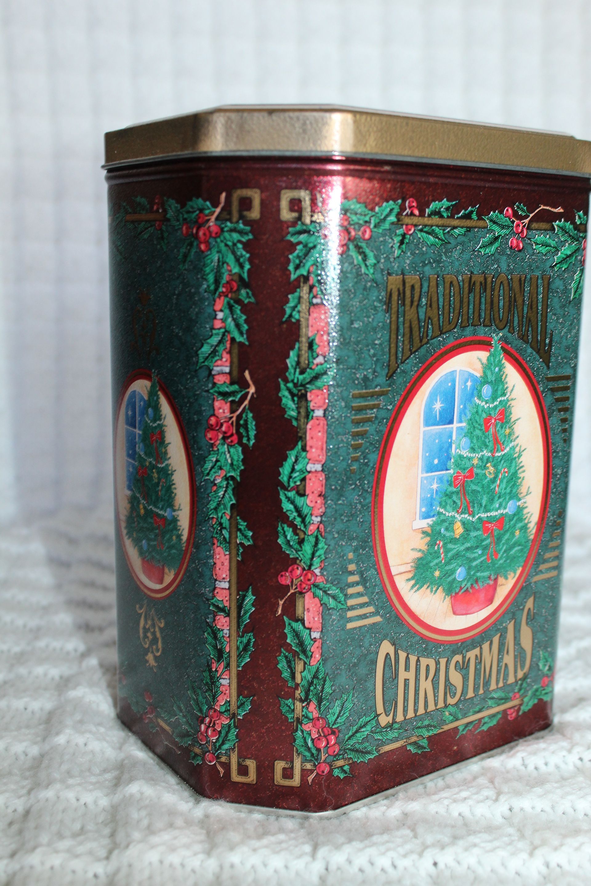 Decorative red and green Christmas tin with holiday tree and garland design