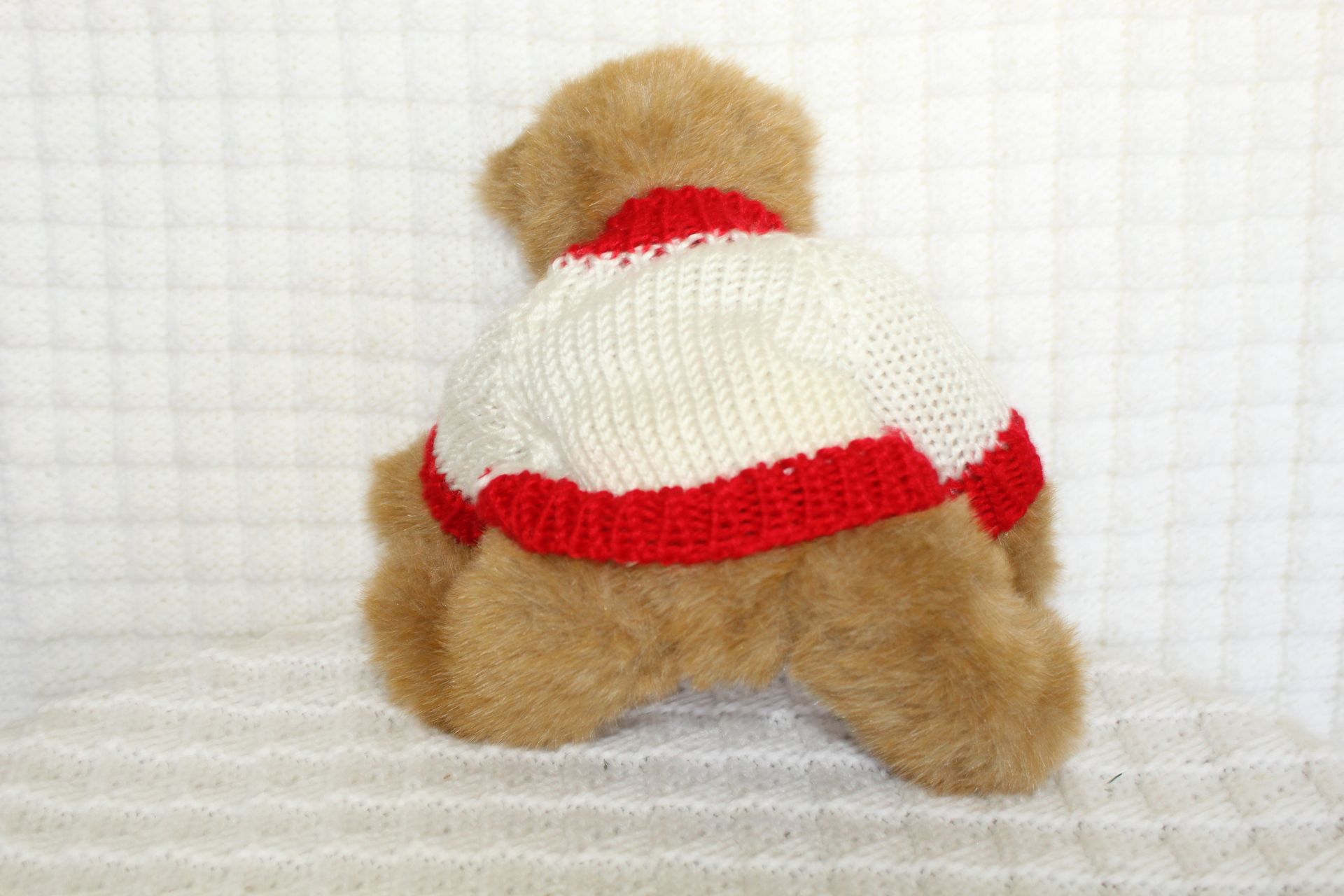 Small teddy bear in a white shirt with red trim and “Grandma” text, sitting on a white textured surface.