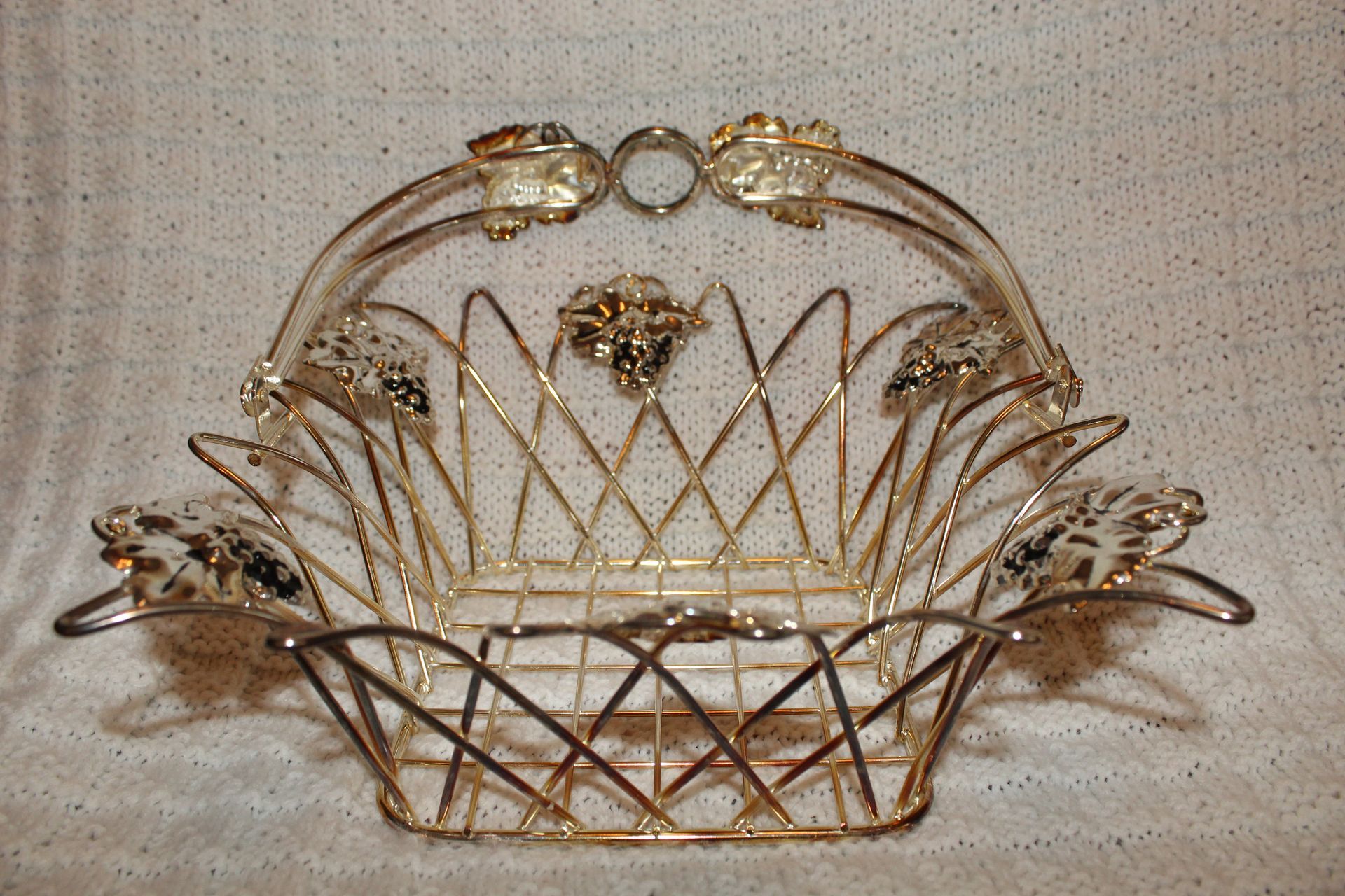 Gold wire basket with floral decorations and a curved handle on a beige background