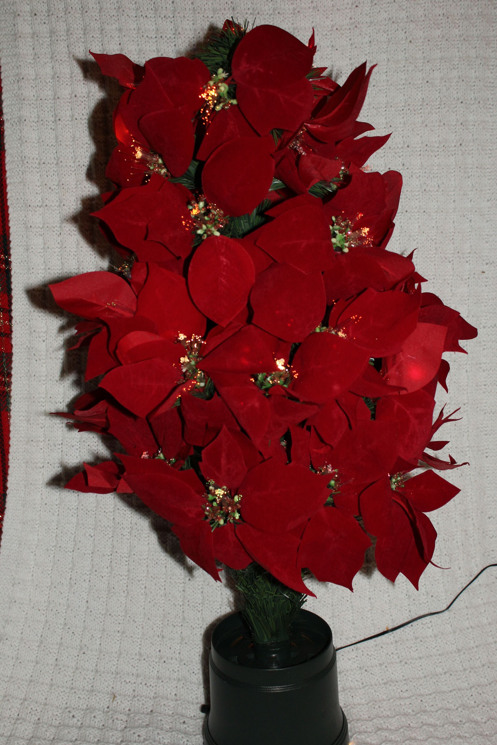 Red poinsettia arrangement in a green vase against a textured wall