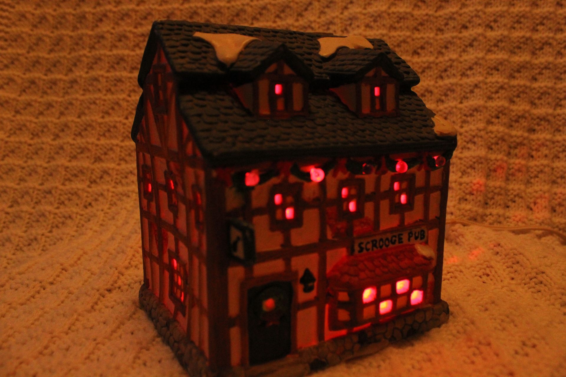 Dickensville Collectables Noma ceramic cottage in a blue box with red logo and snowy roof display.