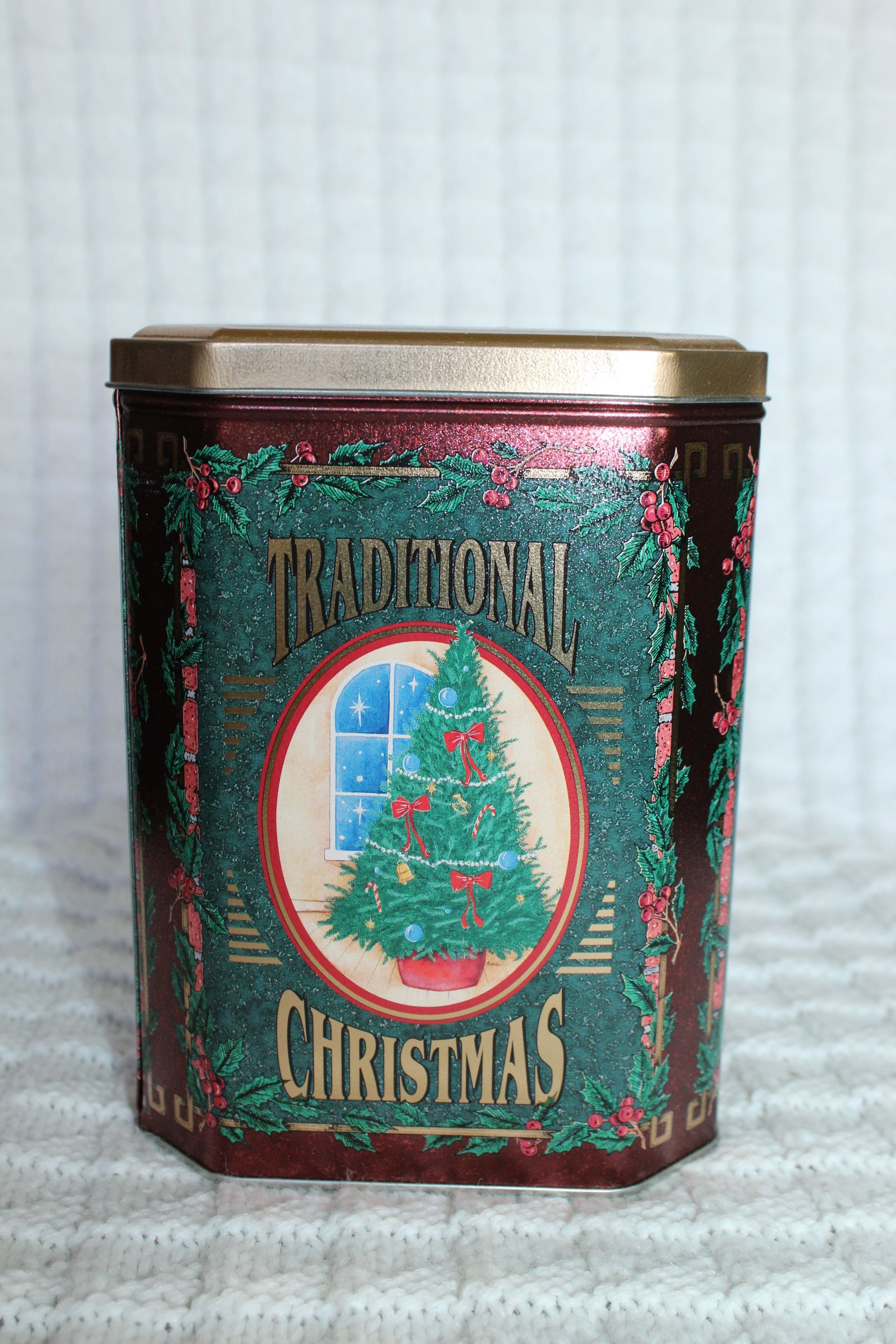 Decorative red and green Christmas tin with holiday tree and garland design