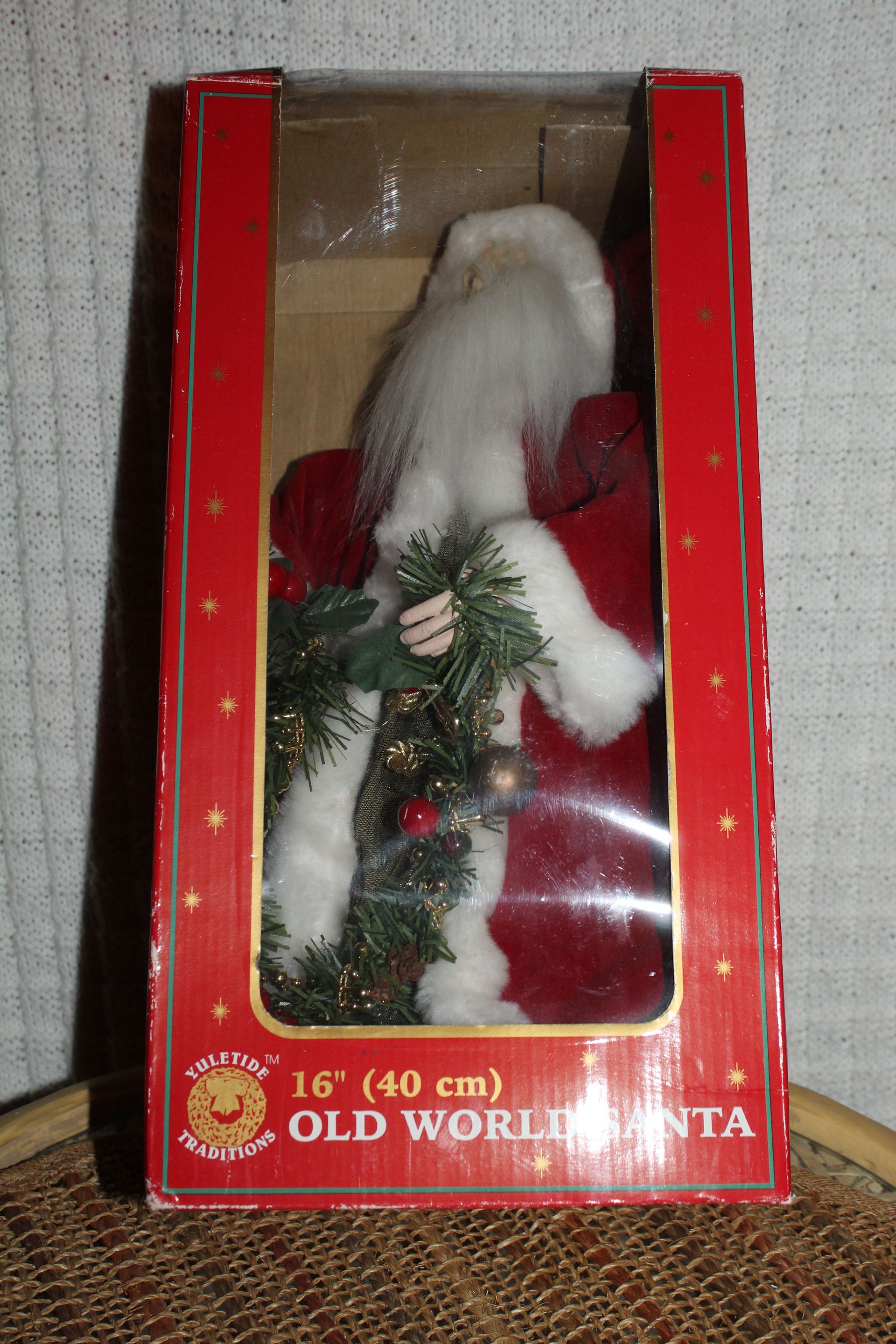 Santa figurine in red suit holding a decorated Christmas tree and wreath in a gold sack