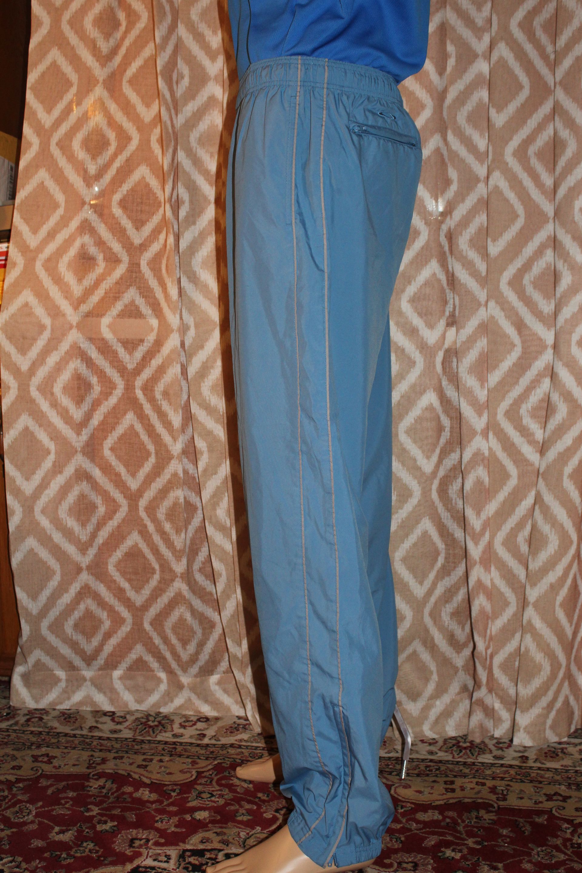 Person wearing blue pants standing in front of a patterned curtain, barefoot on a rug.