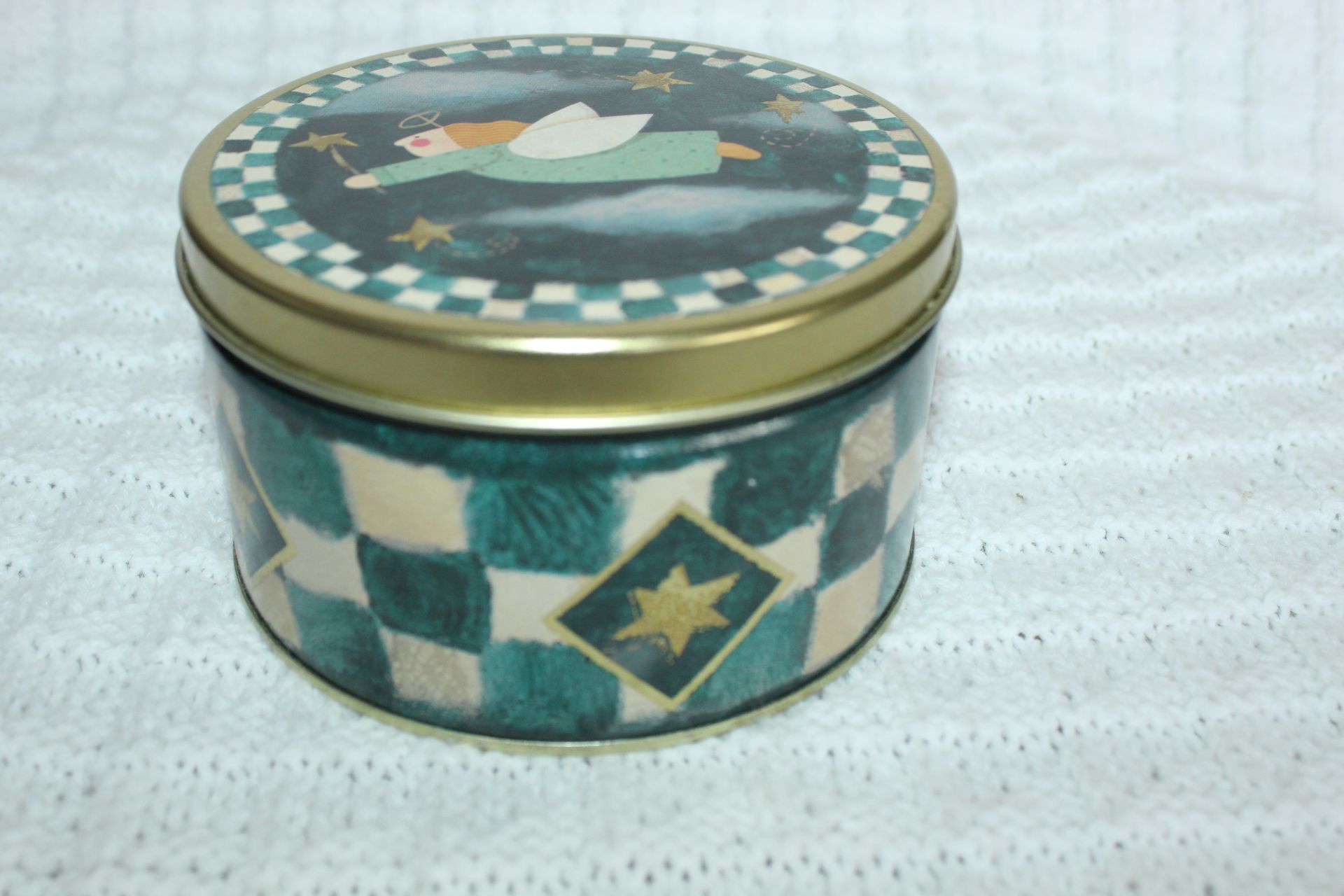 A sleeping angel on a round ornament with a green checkered border and dark cloudy background.