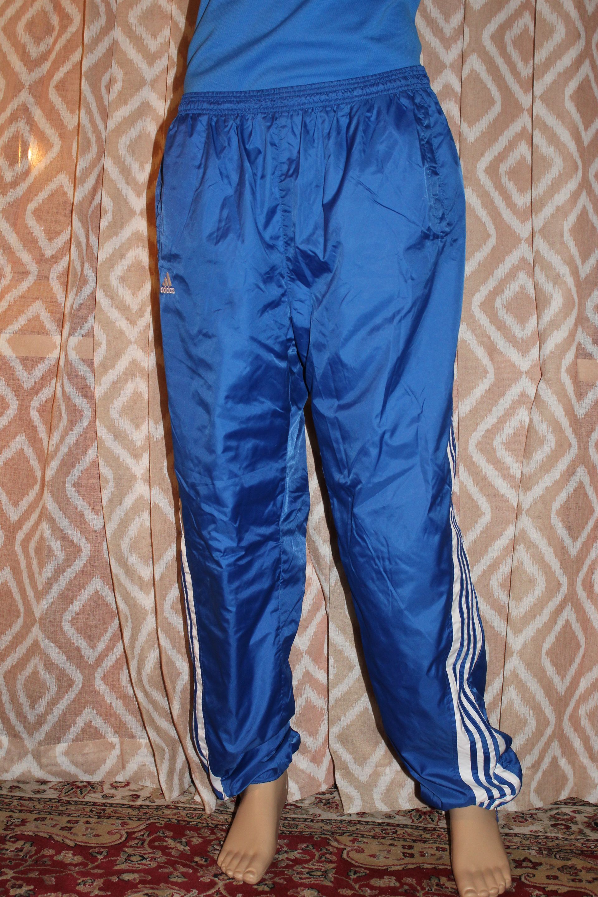 Person wearing blue athletic pants standing indoors against a patterned curtain.