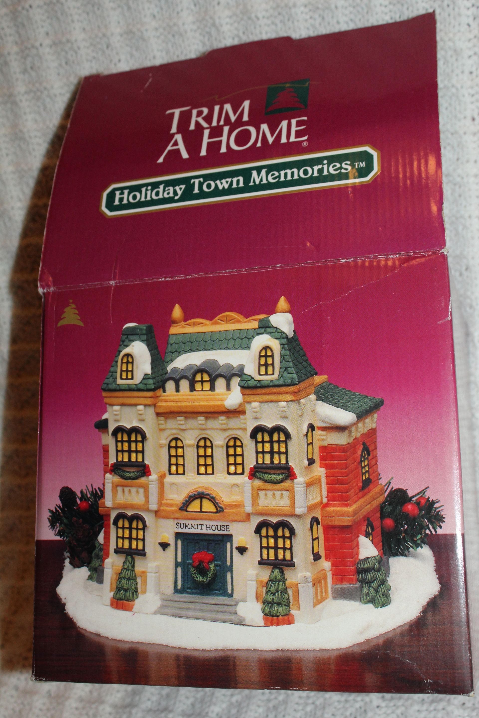 Colorful miniature dollhouse with a teal front door and white facade on a textured cloth background