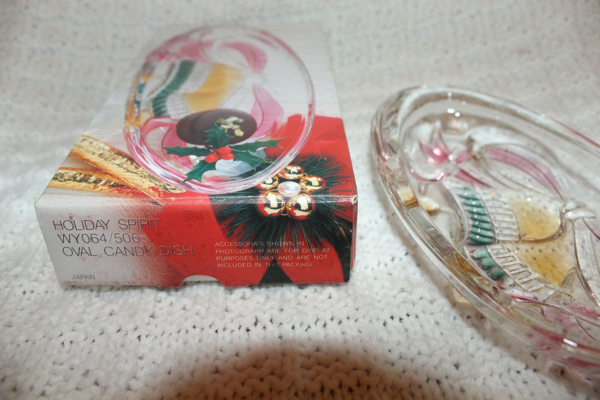 Clear glass oval dish with a colorful fish design on a speckled fabric surface
