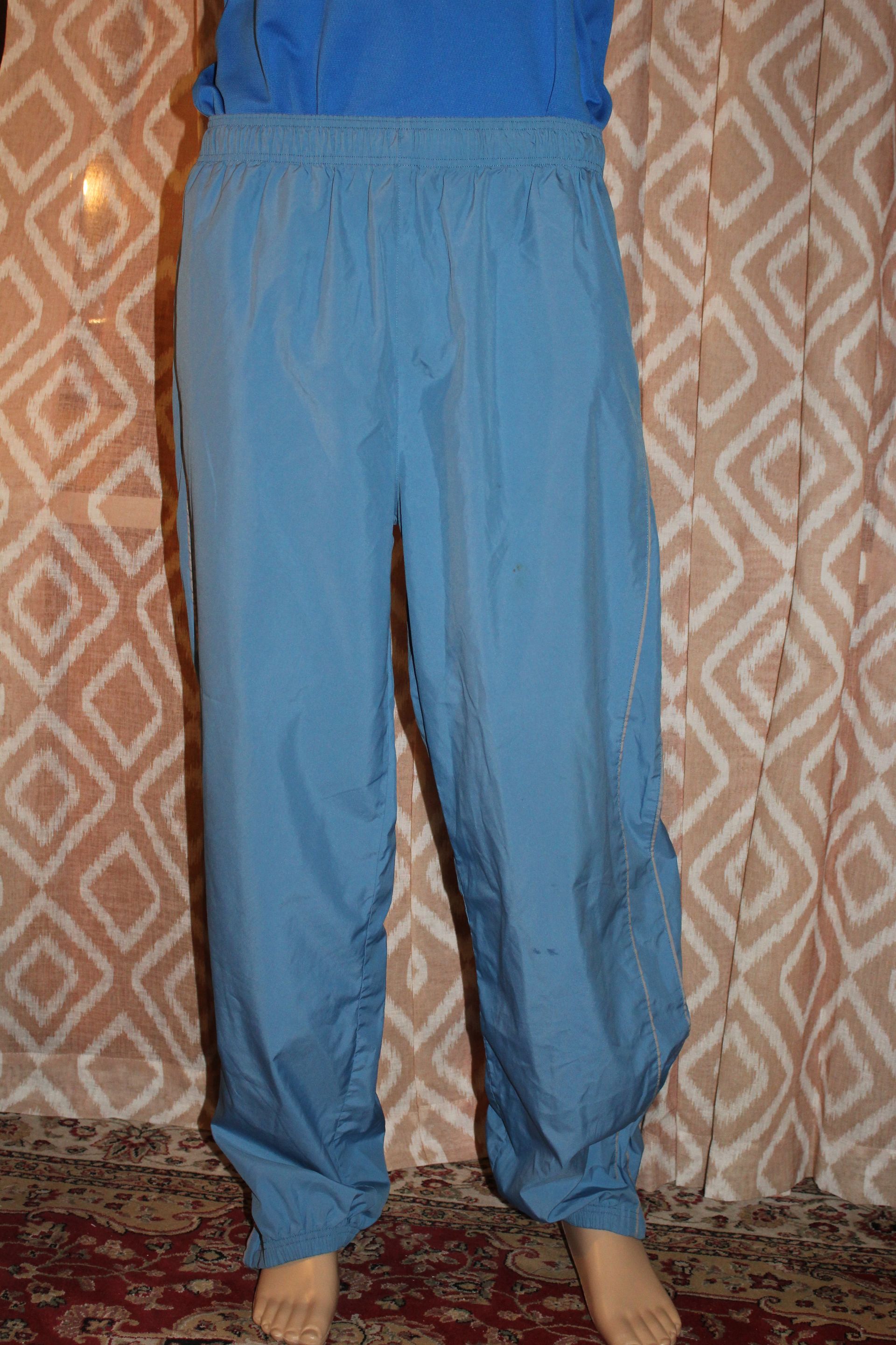 Person wearing blue pants standing in front of a patterned curtain, barefoot on a rug.