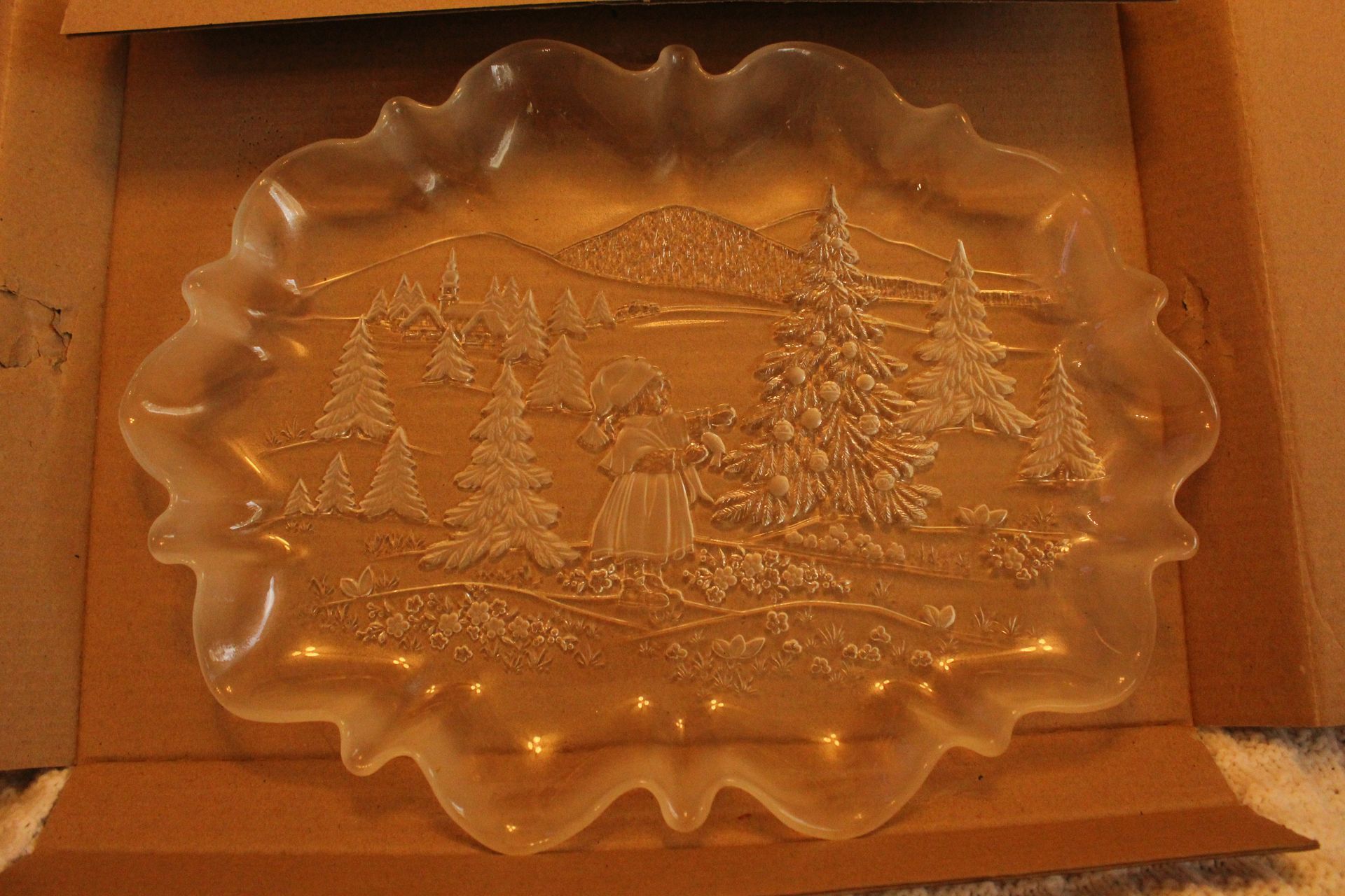 Clear glass platter with scalloped edges and a winter landscape design in a cardboard box