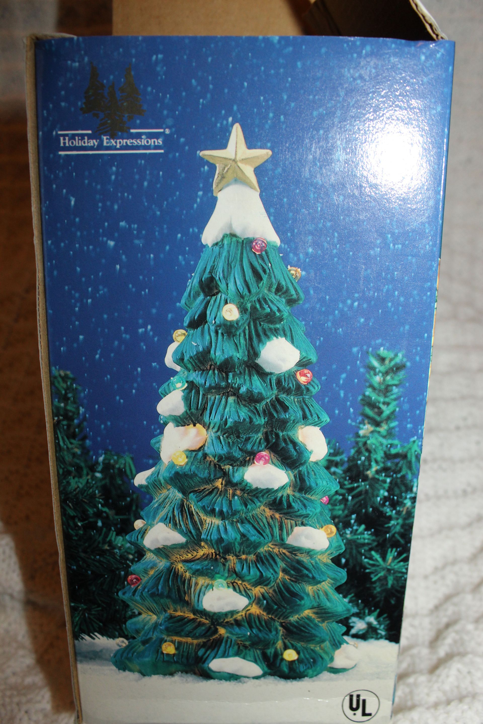 Blue holiday box with a decorated Christmas tree topped by a star and snowy ornaments