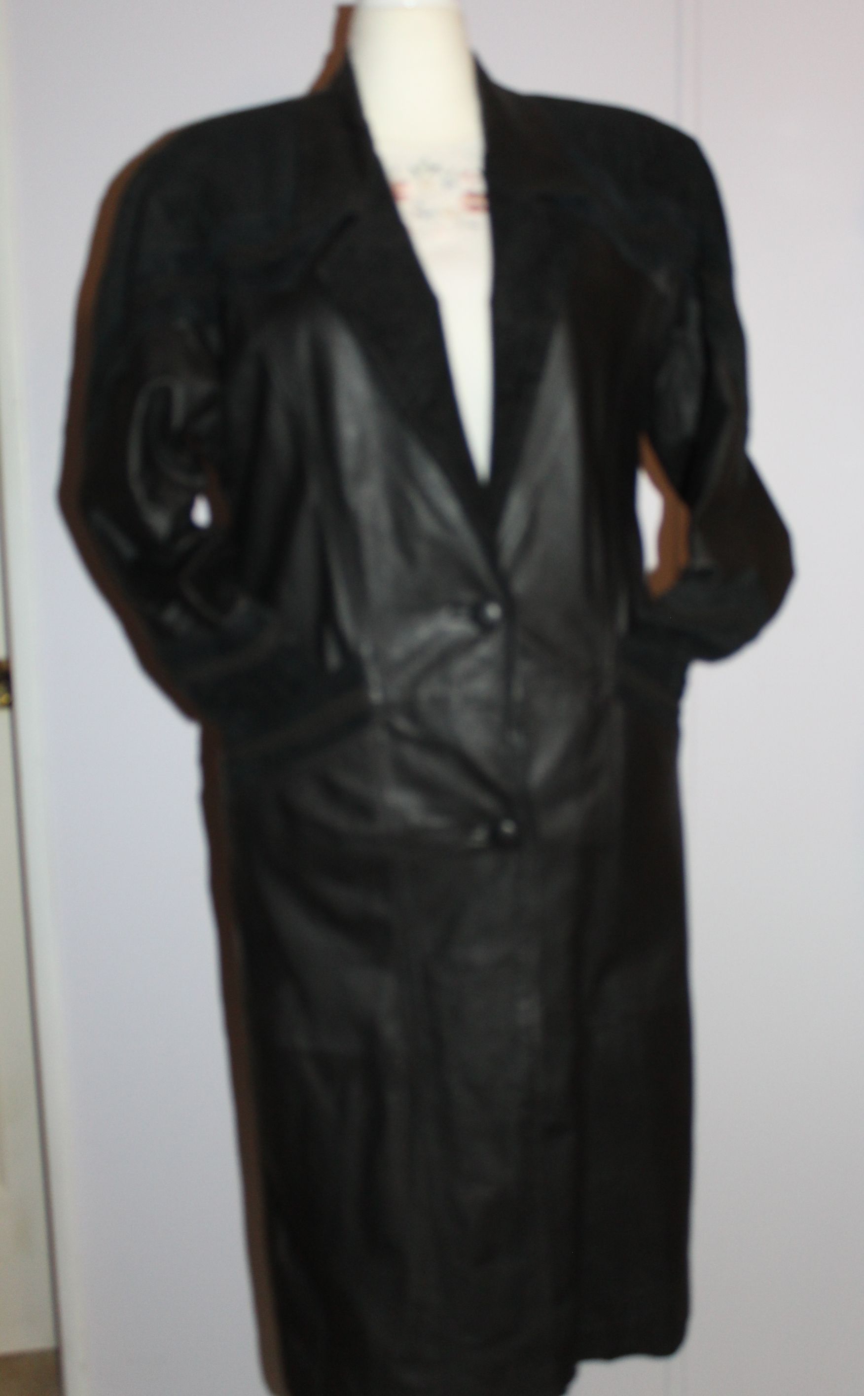 Black leather long coat displayed on a mannequin.