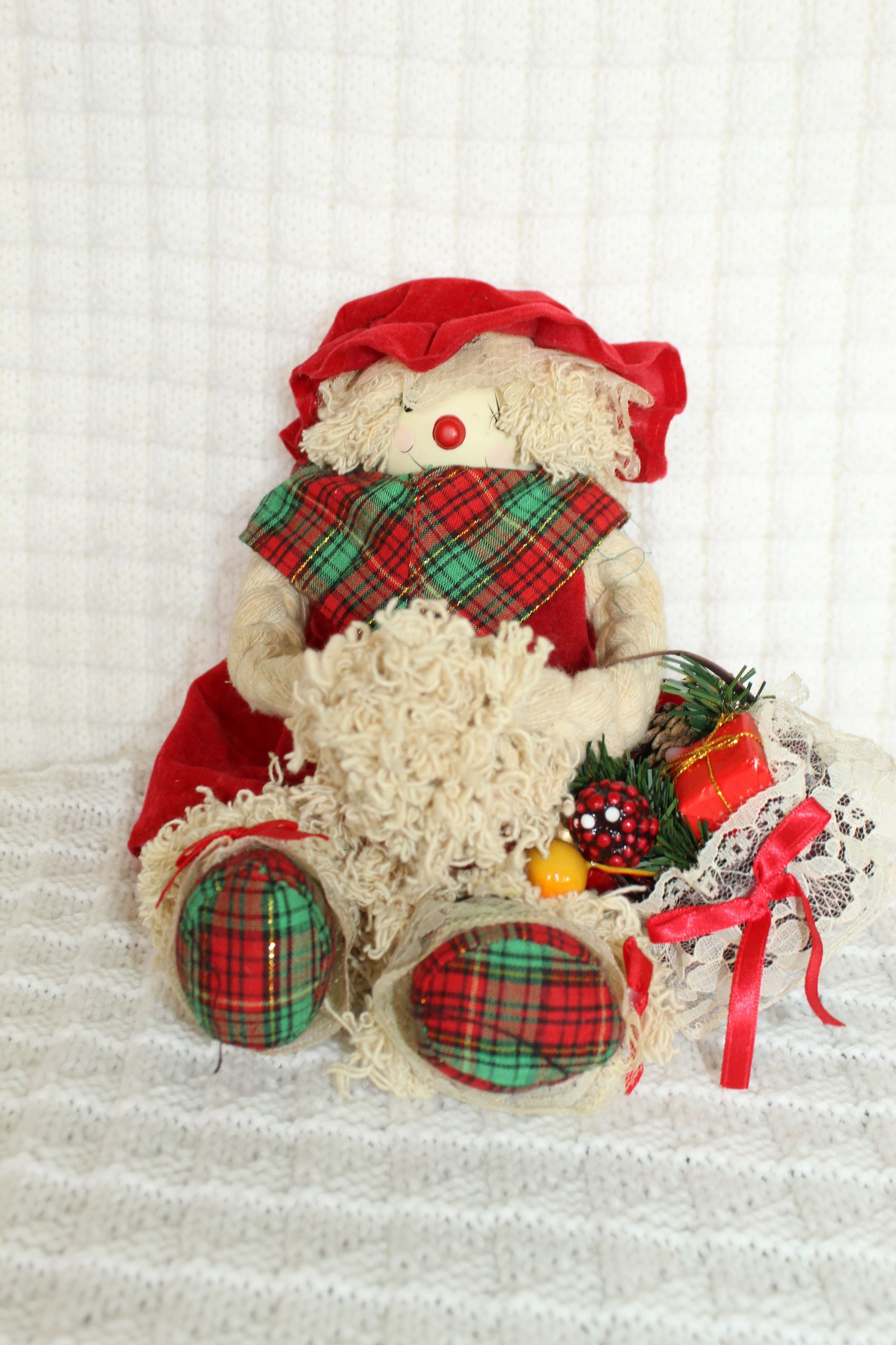 Two Santa Claus plush dolls with gift bags, sitting on a white textured blanket