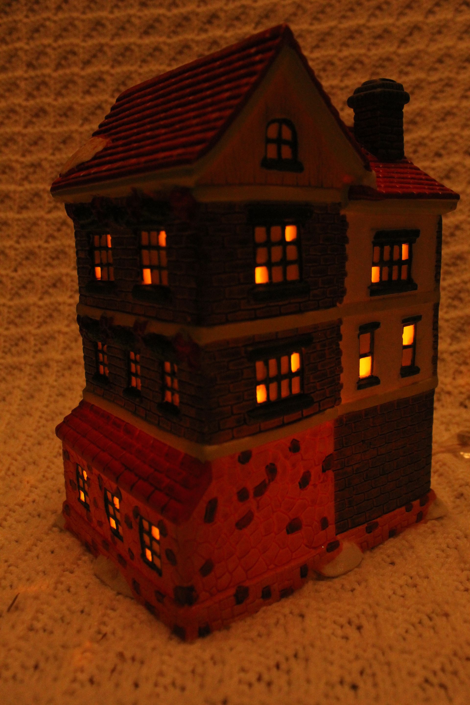 Miniature three-story shop house with red roofs, green doors, and a central staircase in a snowy scene