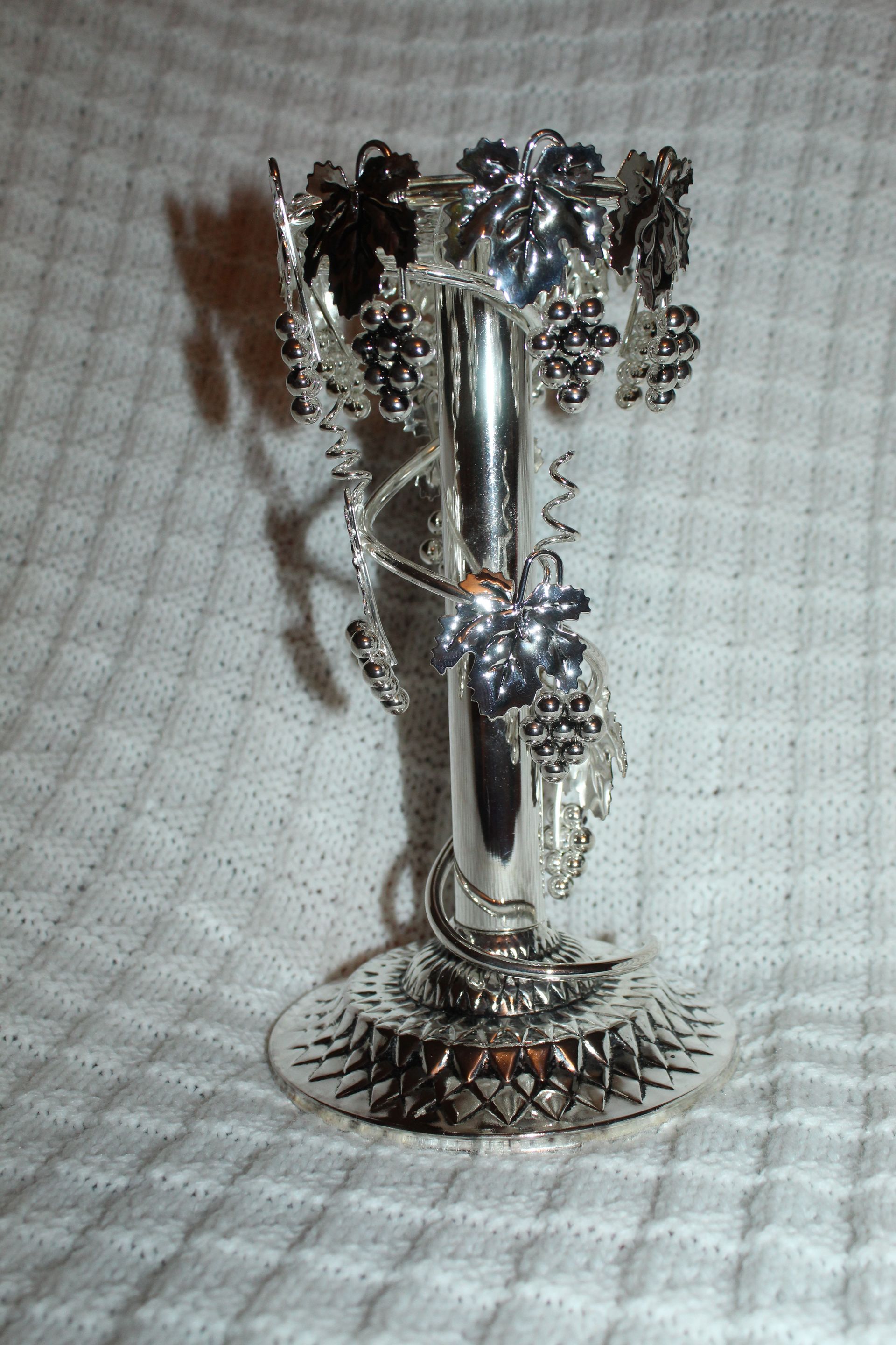 Silver floral figurine vase on a textured white cloth background