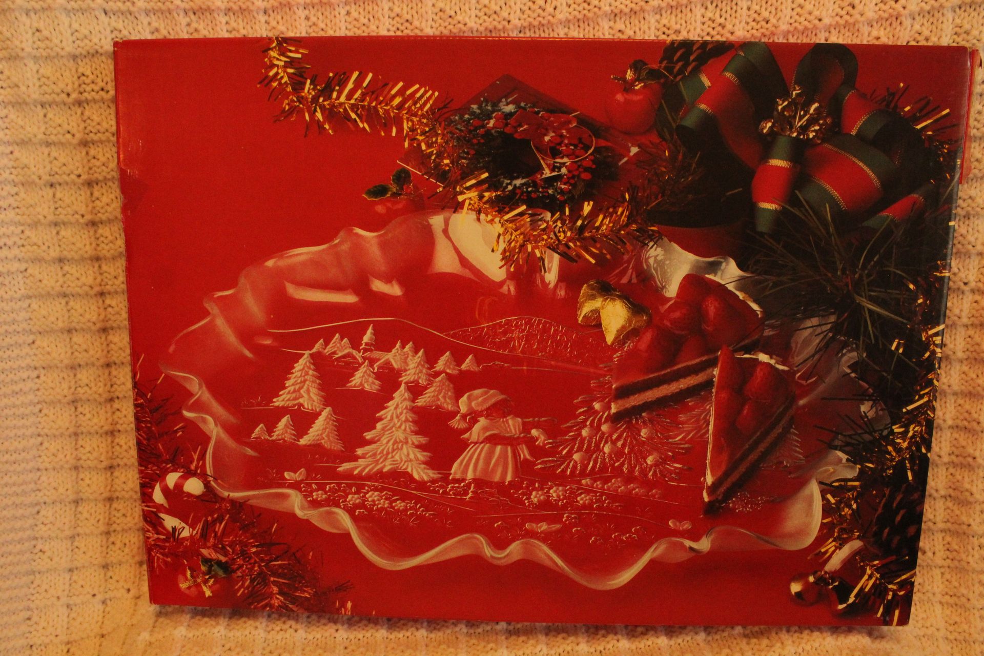 Clear glass platter with scalloped edges and a winter landscape design in a cardboard box