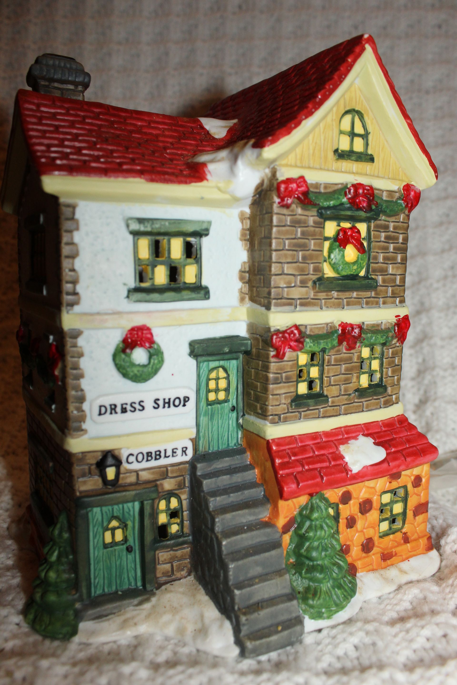 Miniature three-story shop house with red roofs, green doors, and a central staircase in a snowy scene