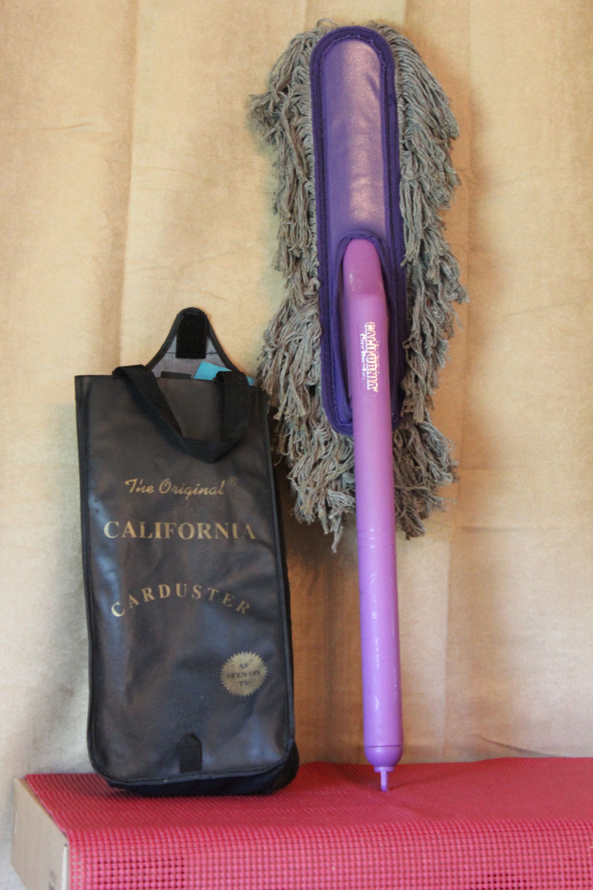 Purple hair straightener beside a black California bag on a beige wall and red surface