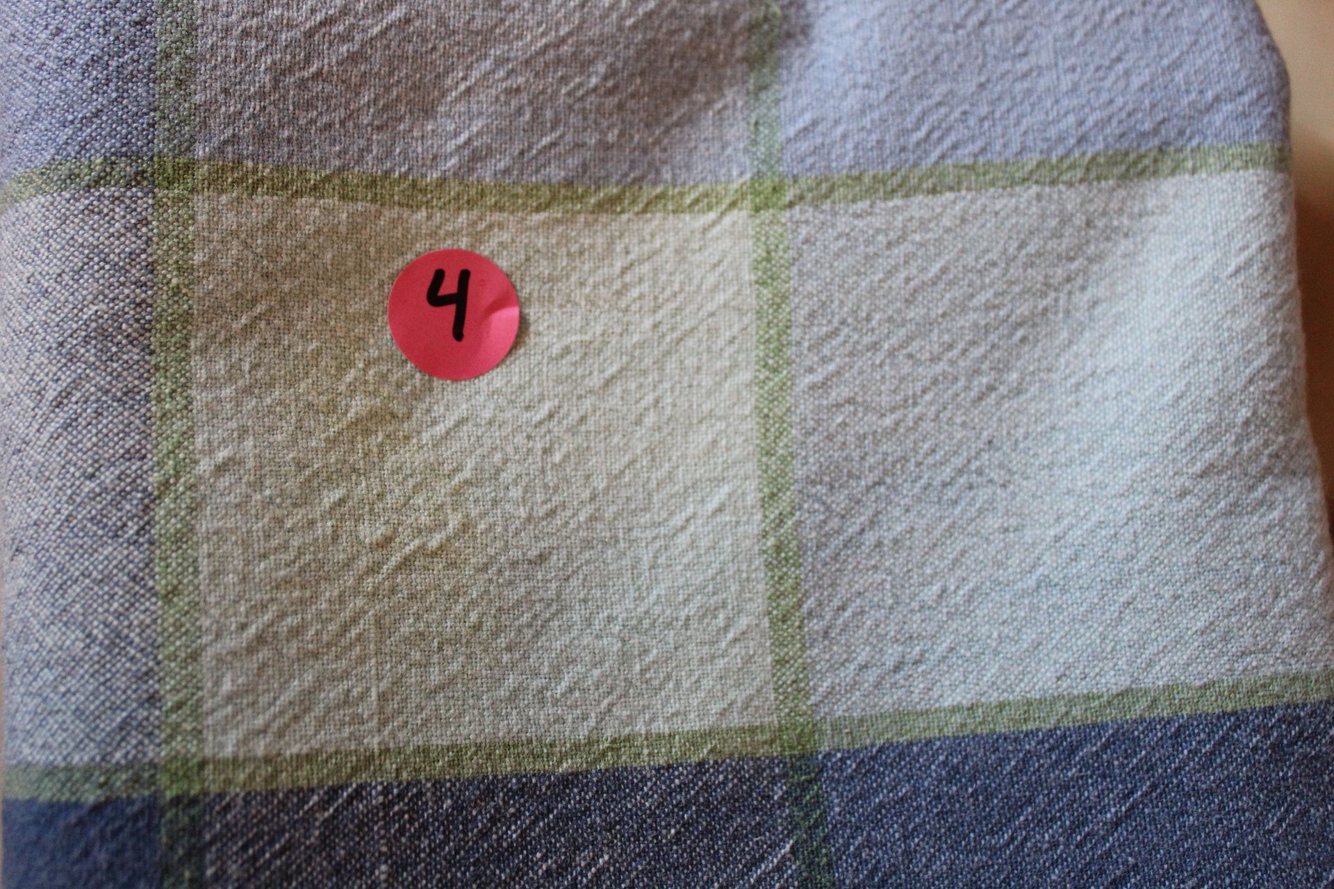 Red “4” sticker on a plaid fabric surface.