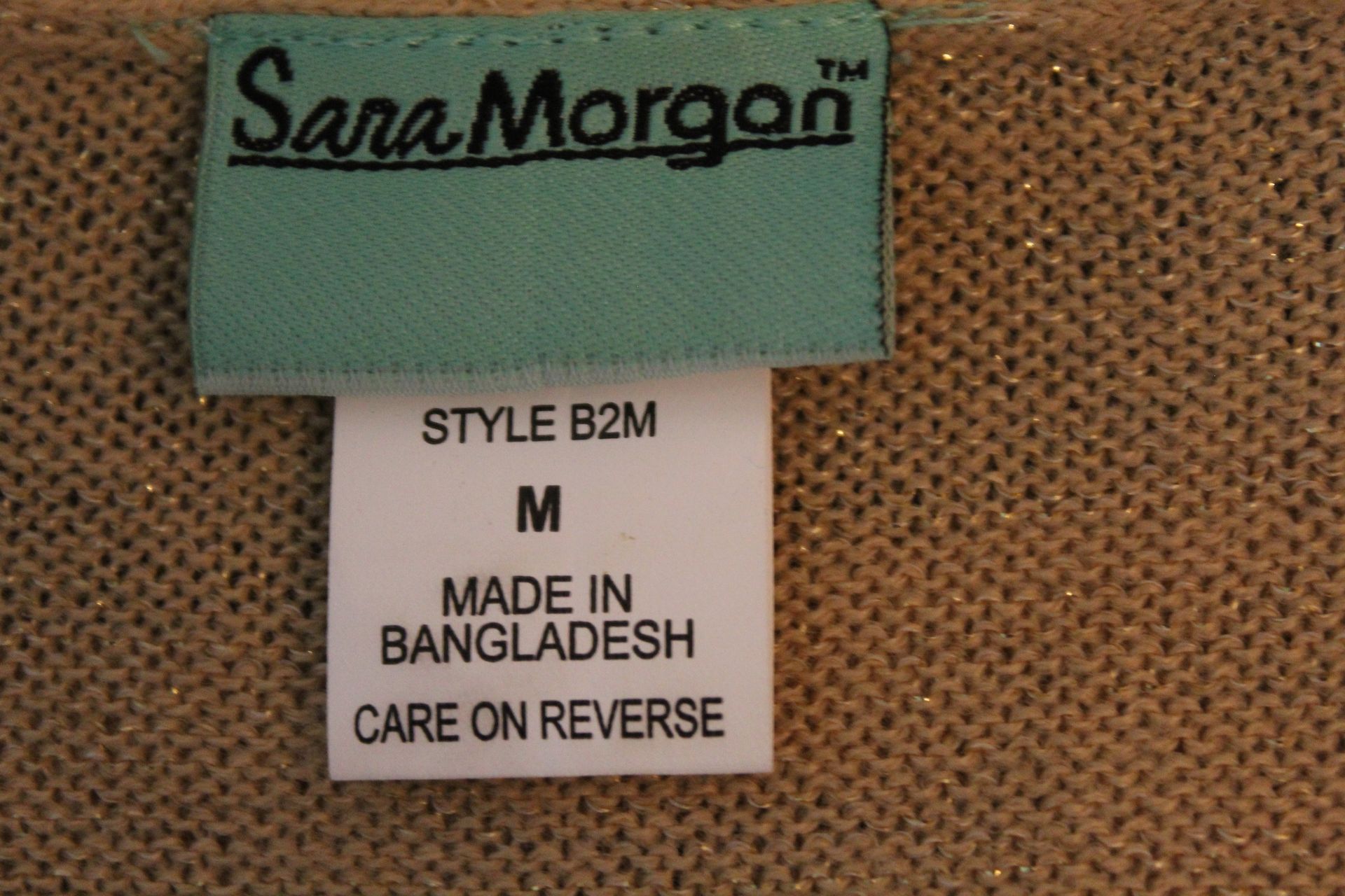 Tan textured beige cardigan on a dress form against a brown backdrop