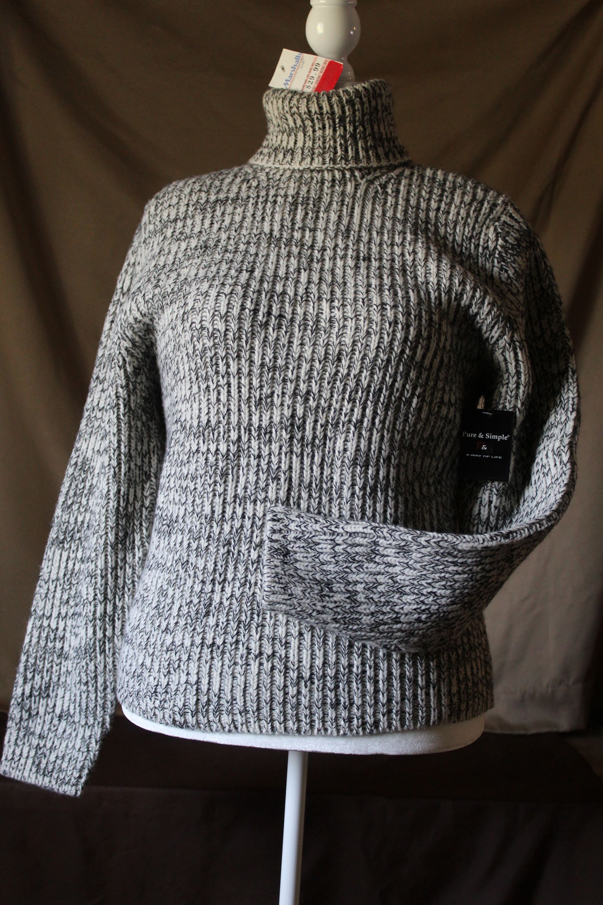 Gray knit turtleneck sweater displayed on a mannequin against a dark background.