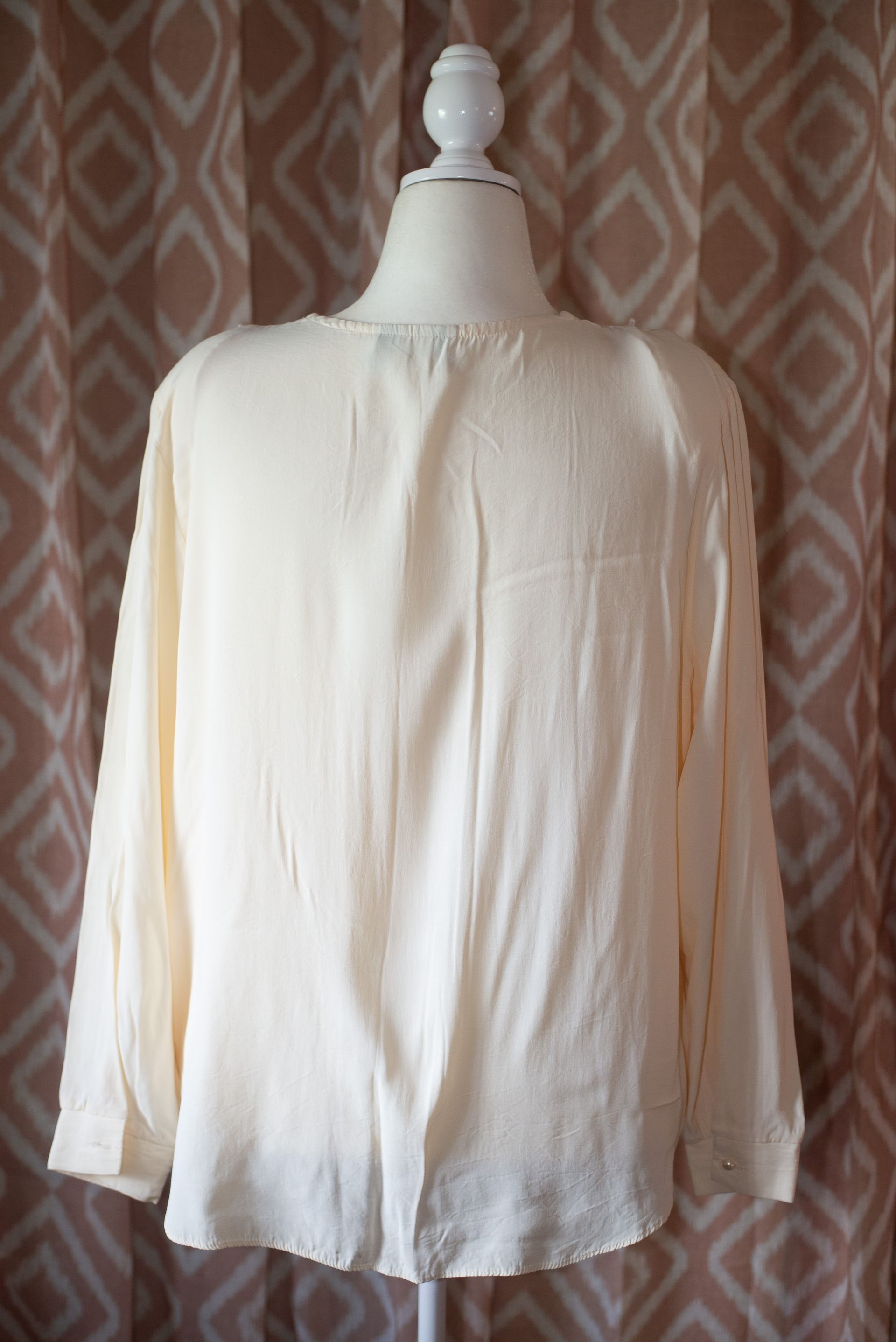 Cream button-up blouse with lace trim on the collar, displayed on a mannequin