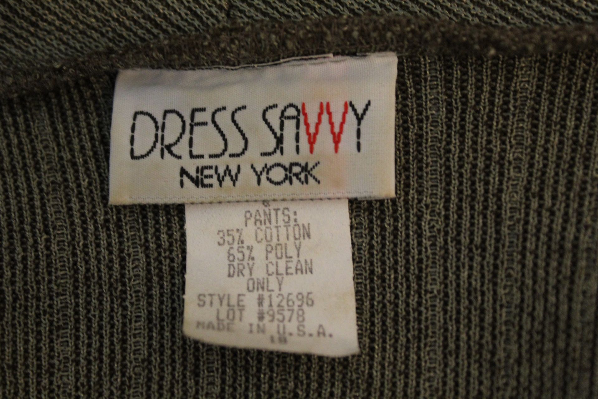 Gray patterned jacket and matching top displayed on a mannequin against a brown backdrop.