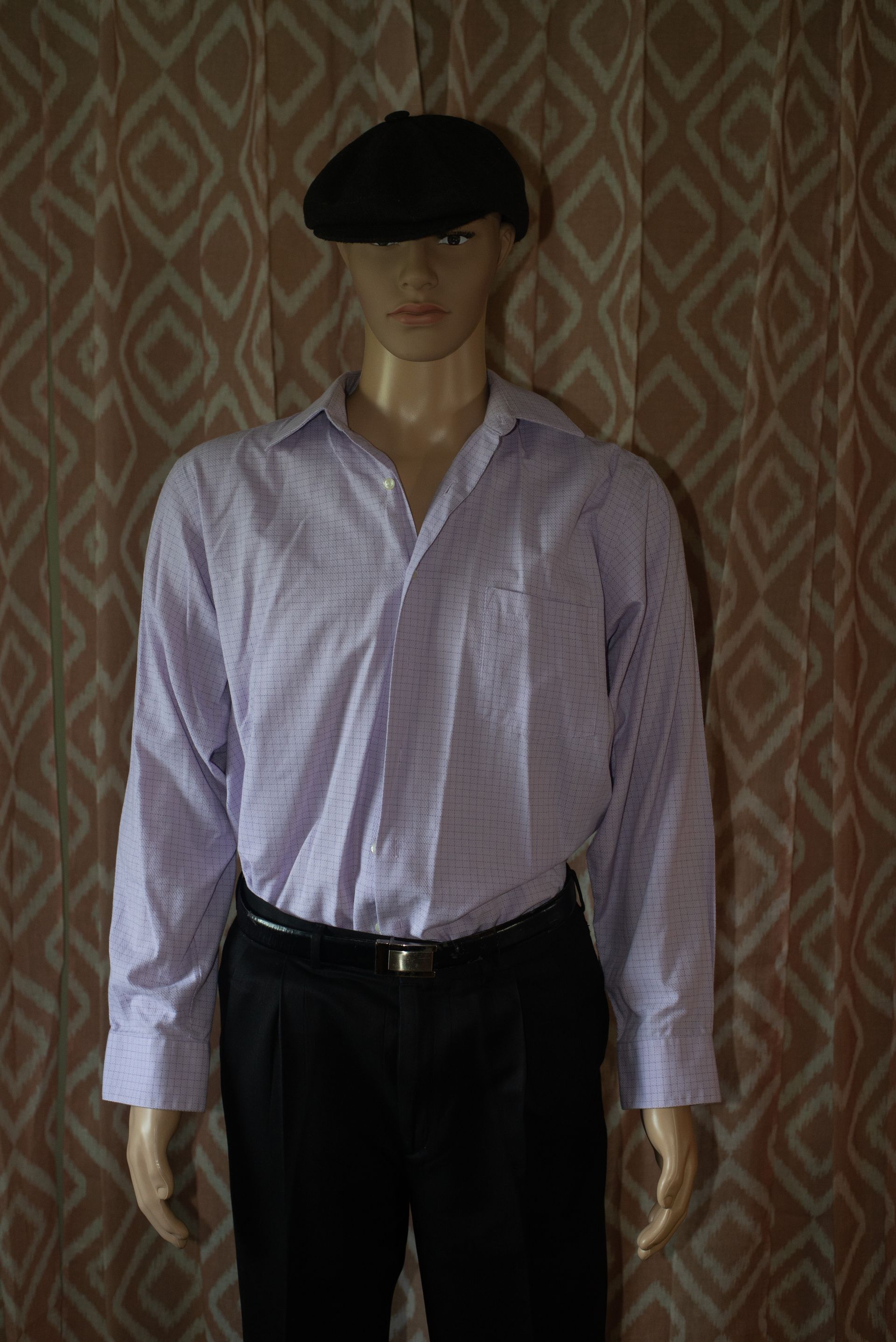 Mannequin in a light purple striped shirt, black pants, and black beret against a patterned backdrop