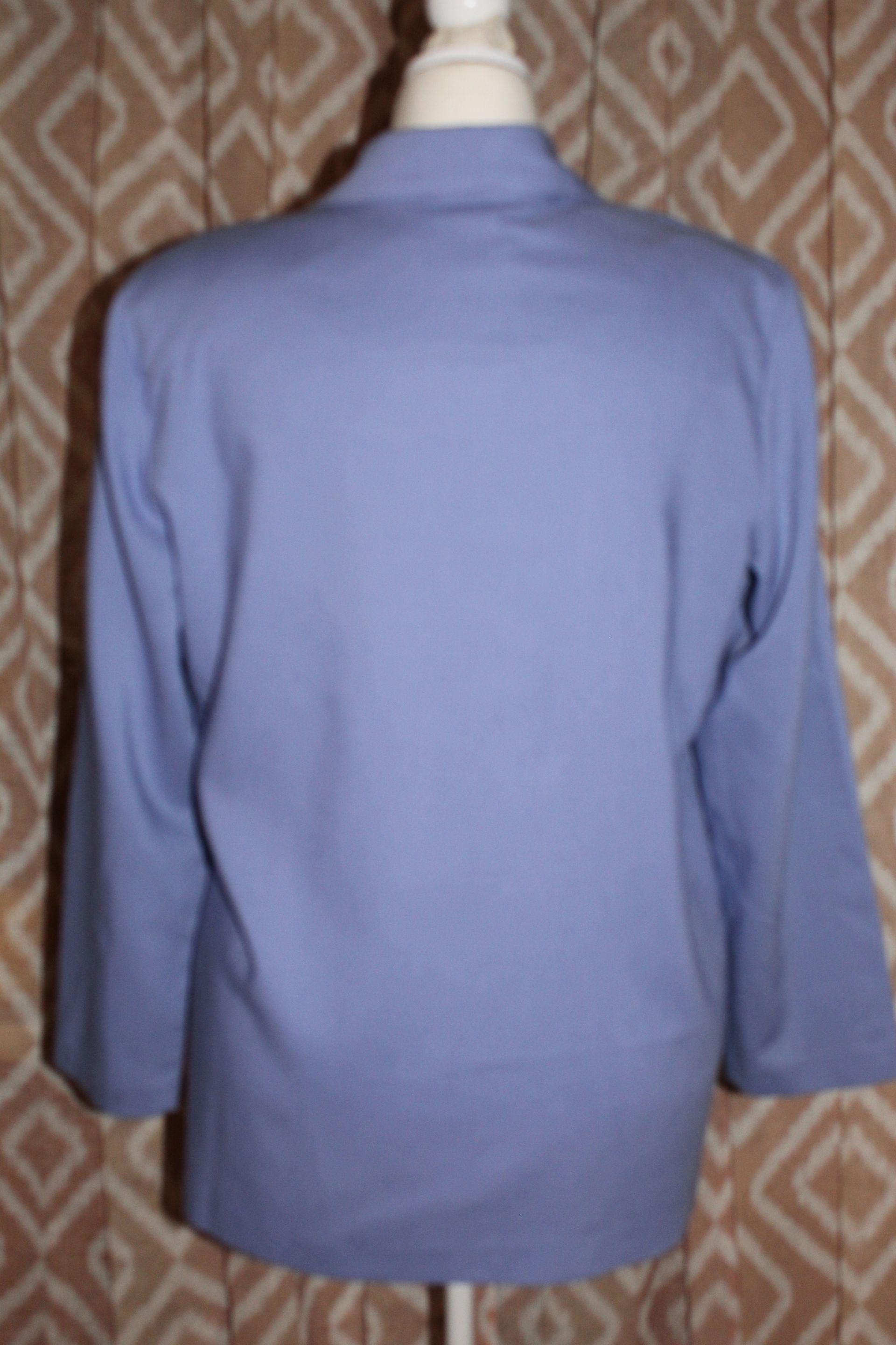 Light blue blazer on a mannequin against a patterned background
