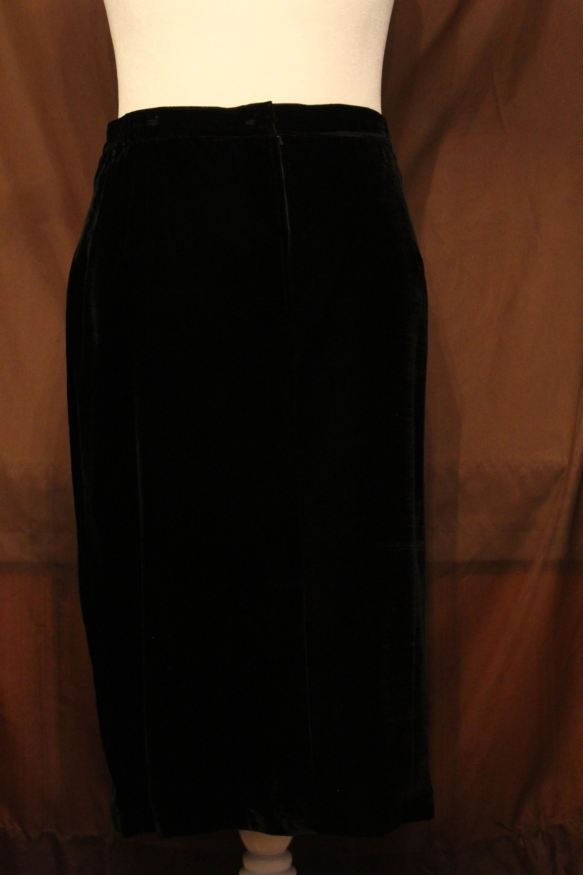 Black dress and jacket ensemble with gold beadwork displayed against a peach backdrop