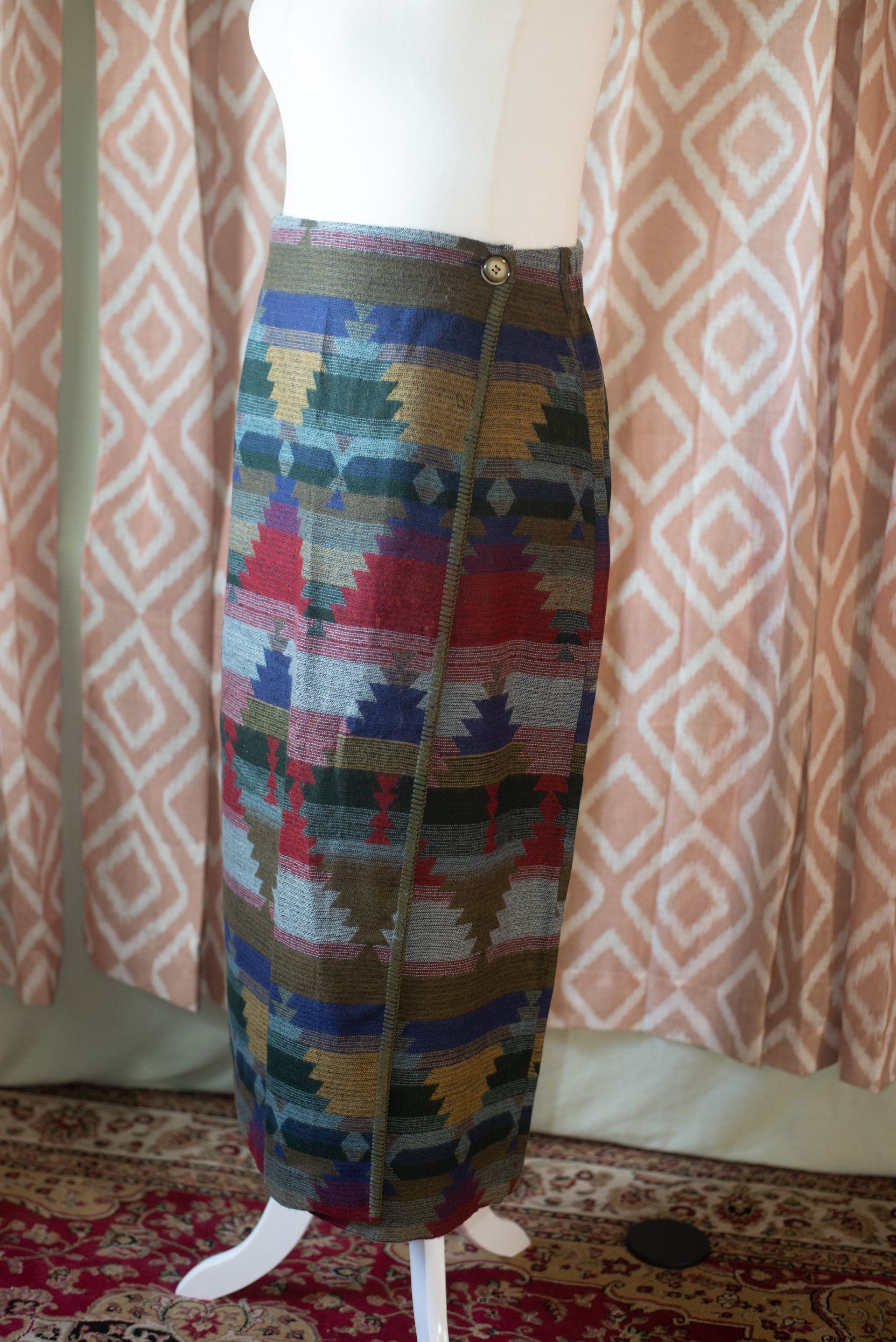 Colorful patterned blazer and skirt set displayed on a mannequin in front of curtains