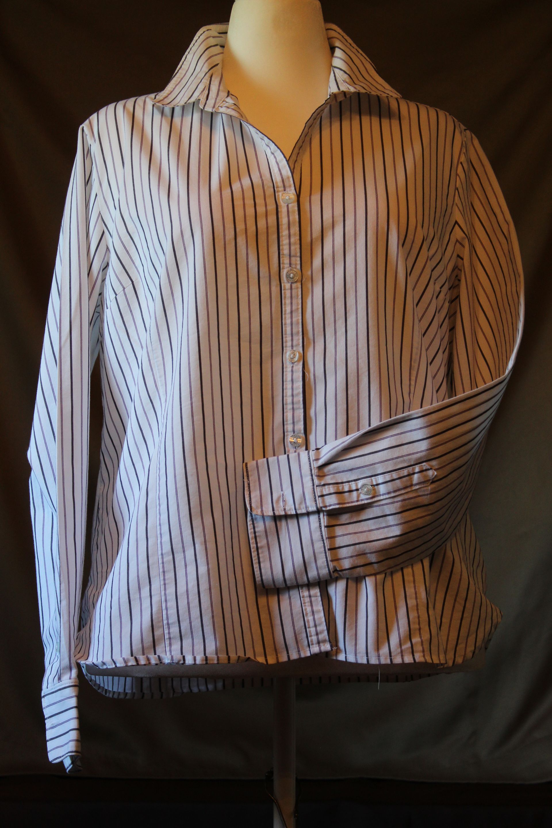 Striped long-sleeve button-up shirt on a mannequin, white with thin red and blue vertical lines.
