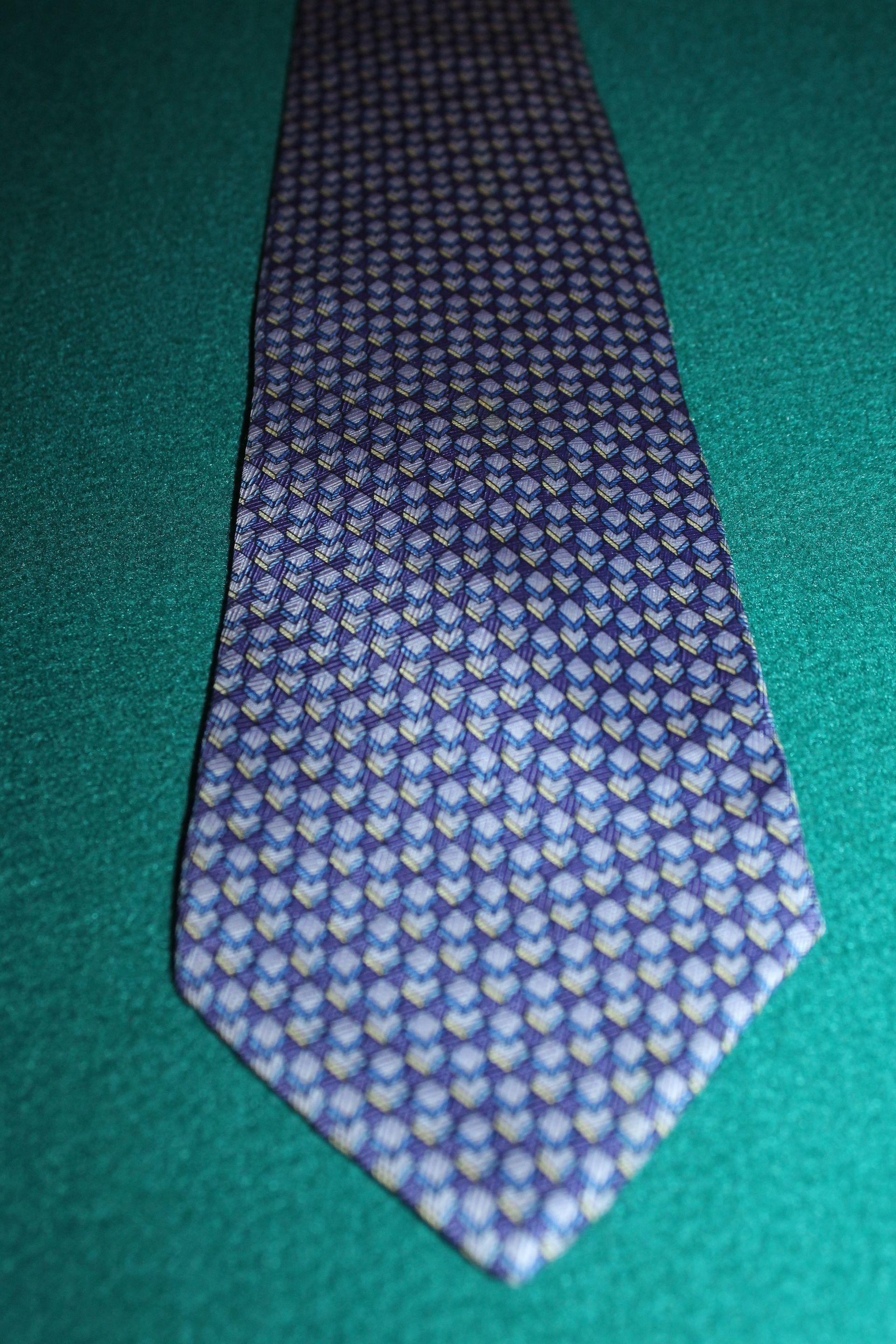 Purple patterned necktie on a green fabric background