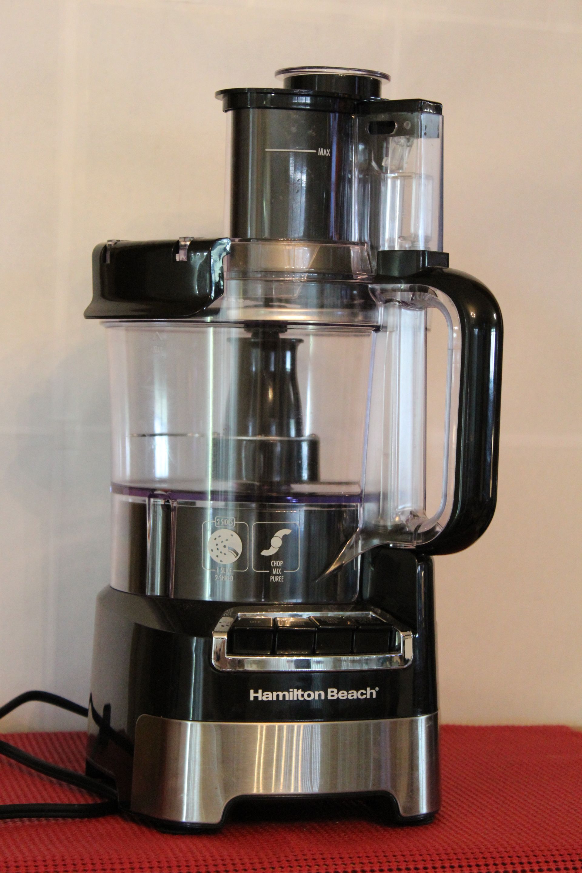 Black and stainless steel food processor on a red surface