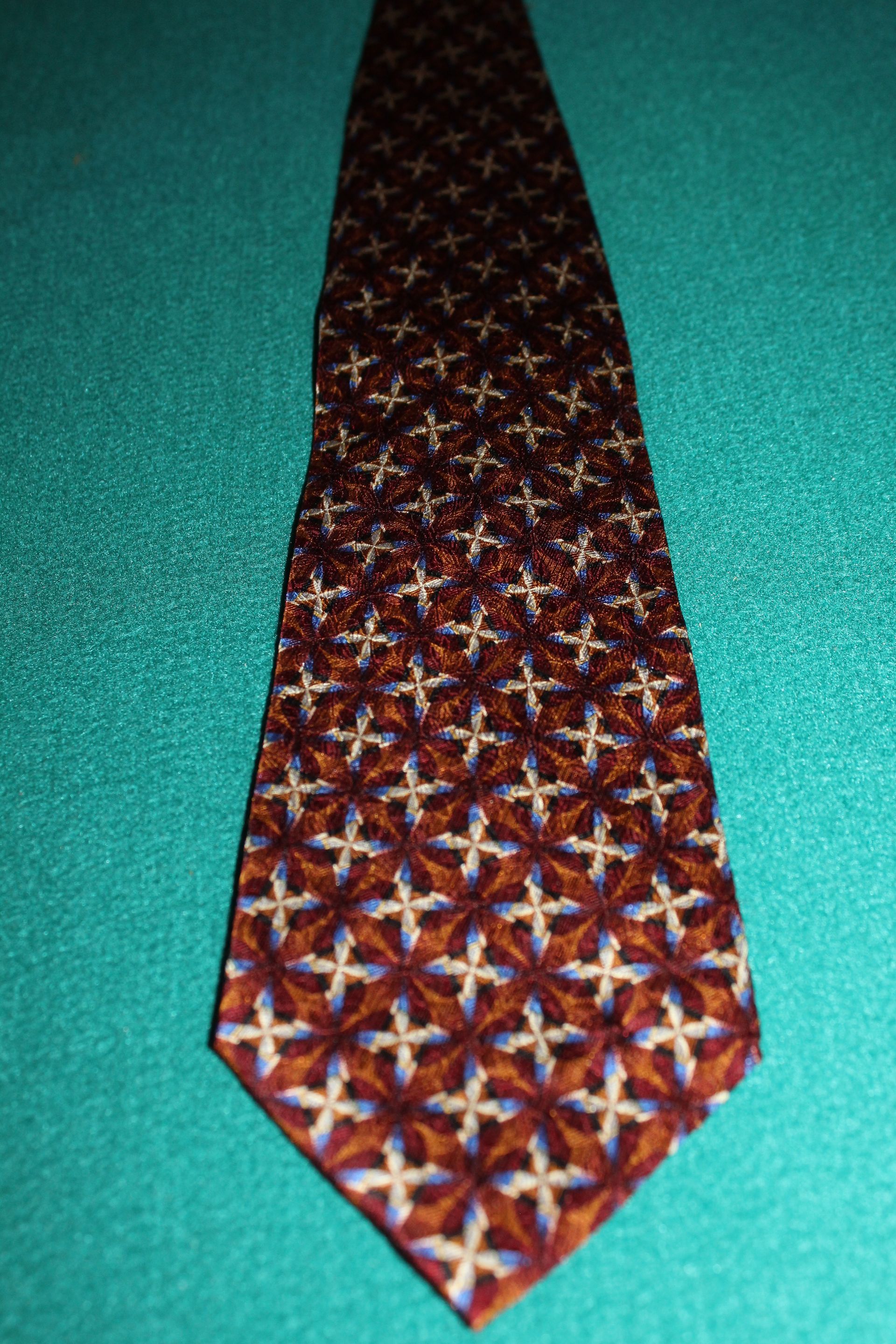 Patterned red and gold necktie on a teal background