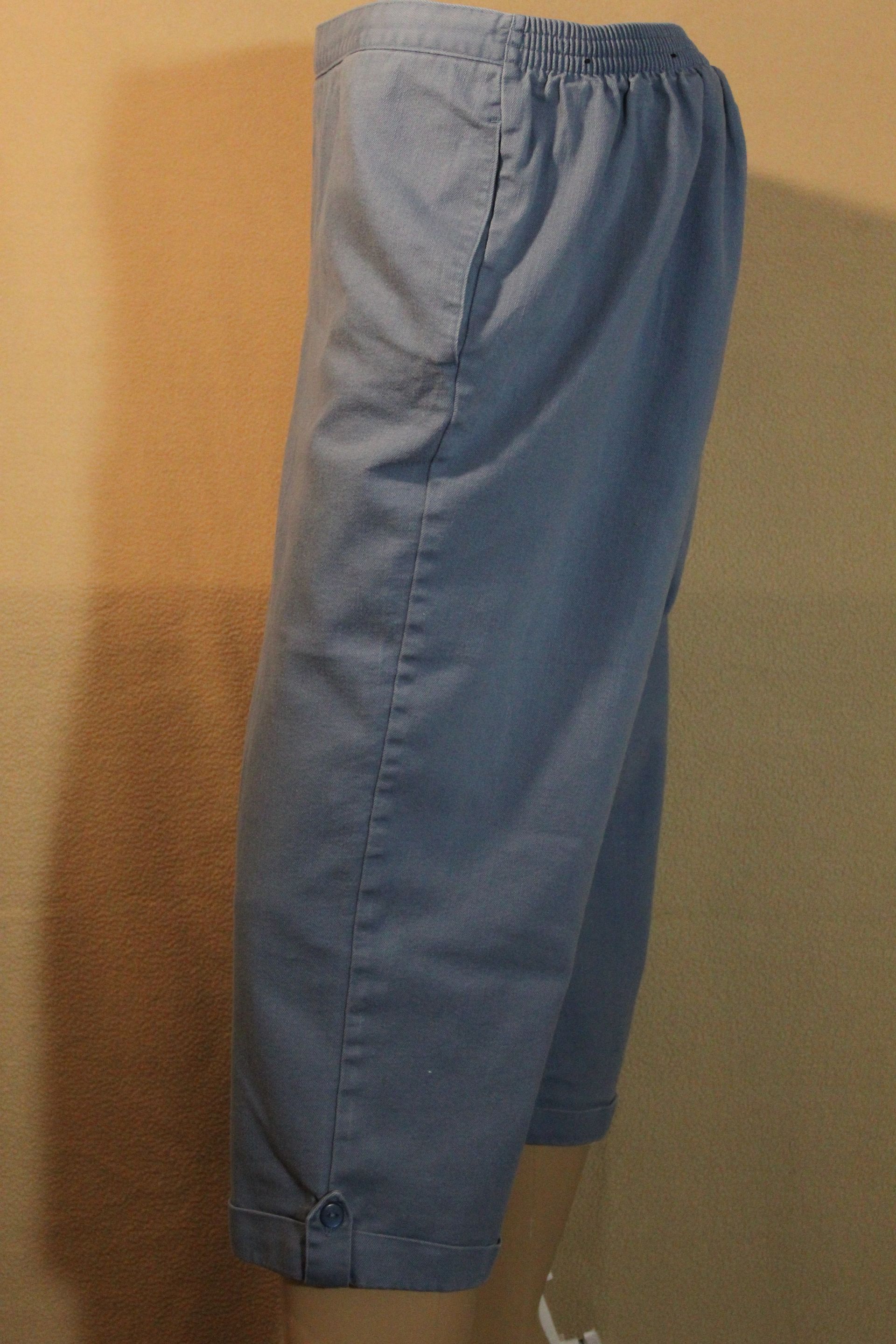 Blue-gray cropped pants displayed against a plain tan background.