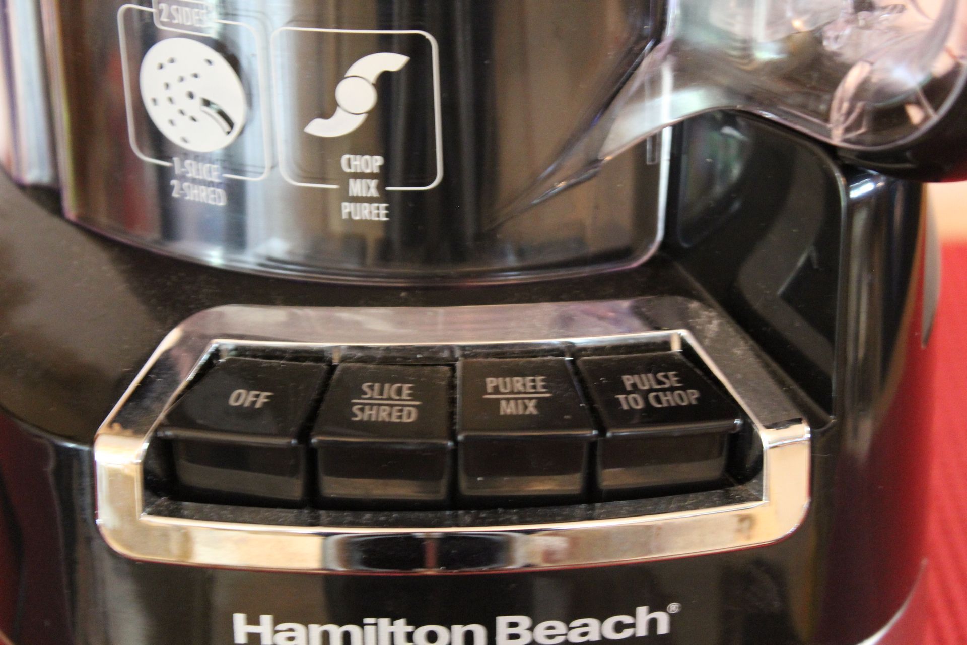 Black and stainless steel food processor on a red surface