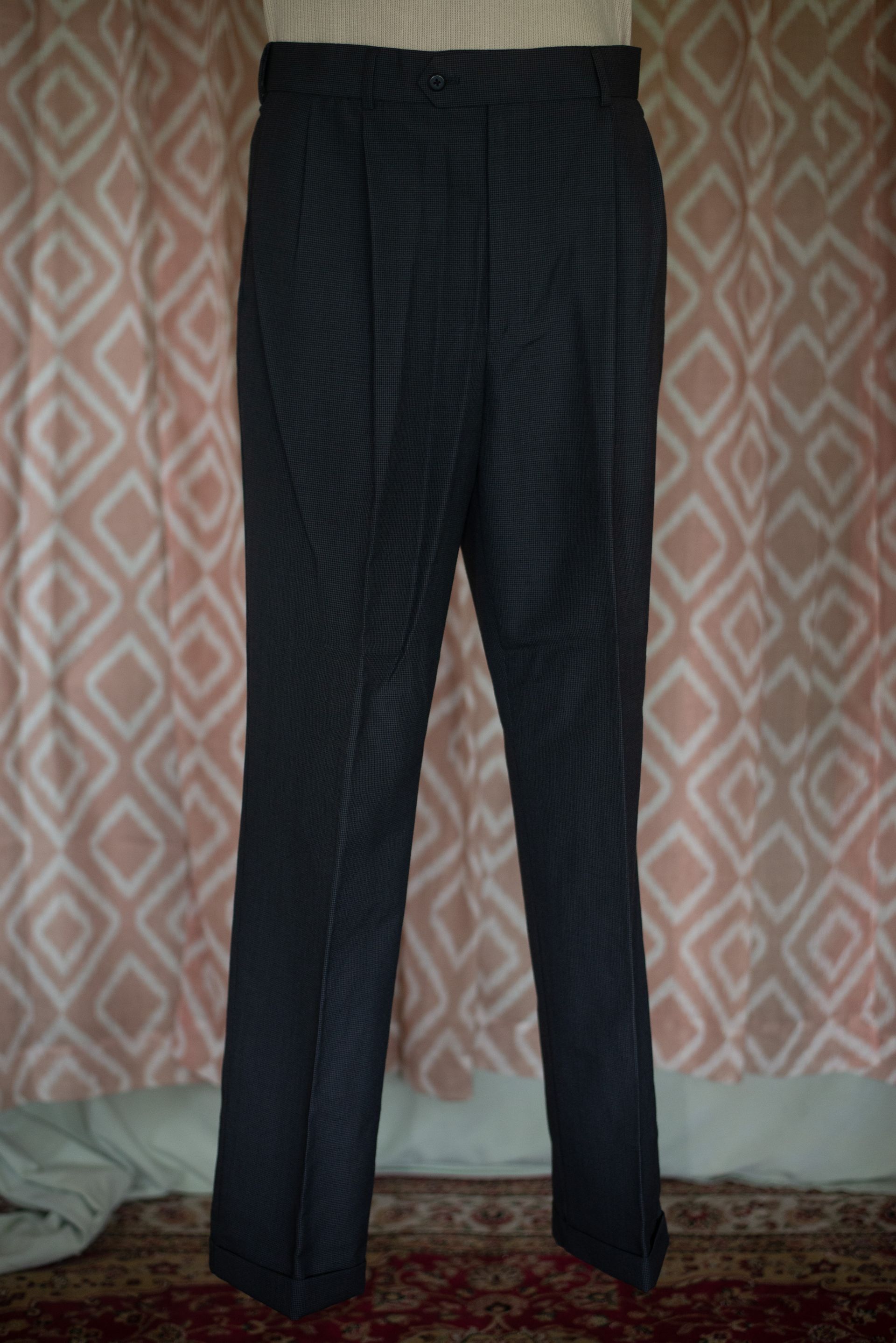 Dark striped trousers hanging against a patterned wall.