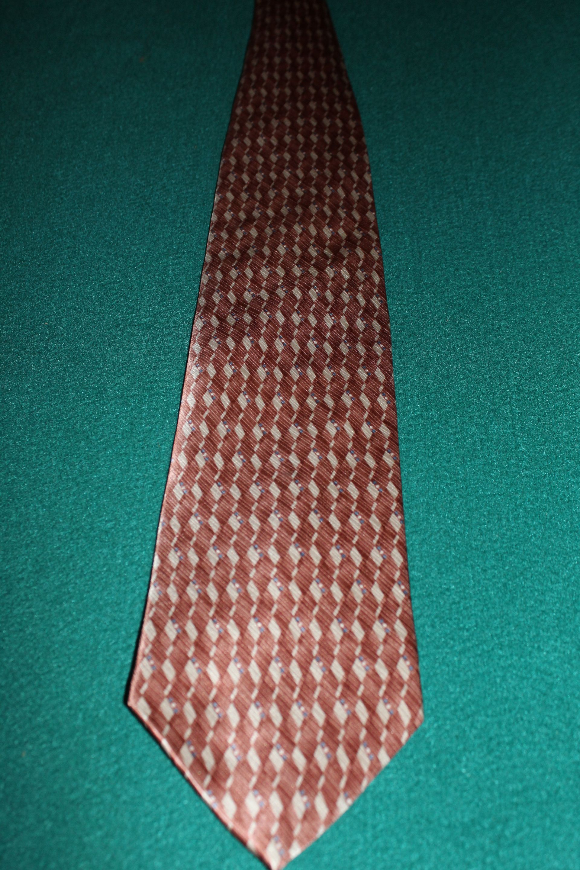 Red patterned necktie on a teal surface.
