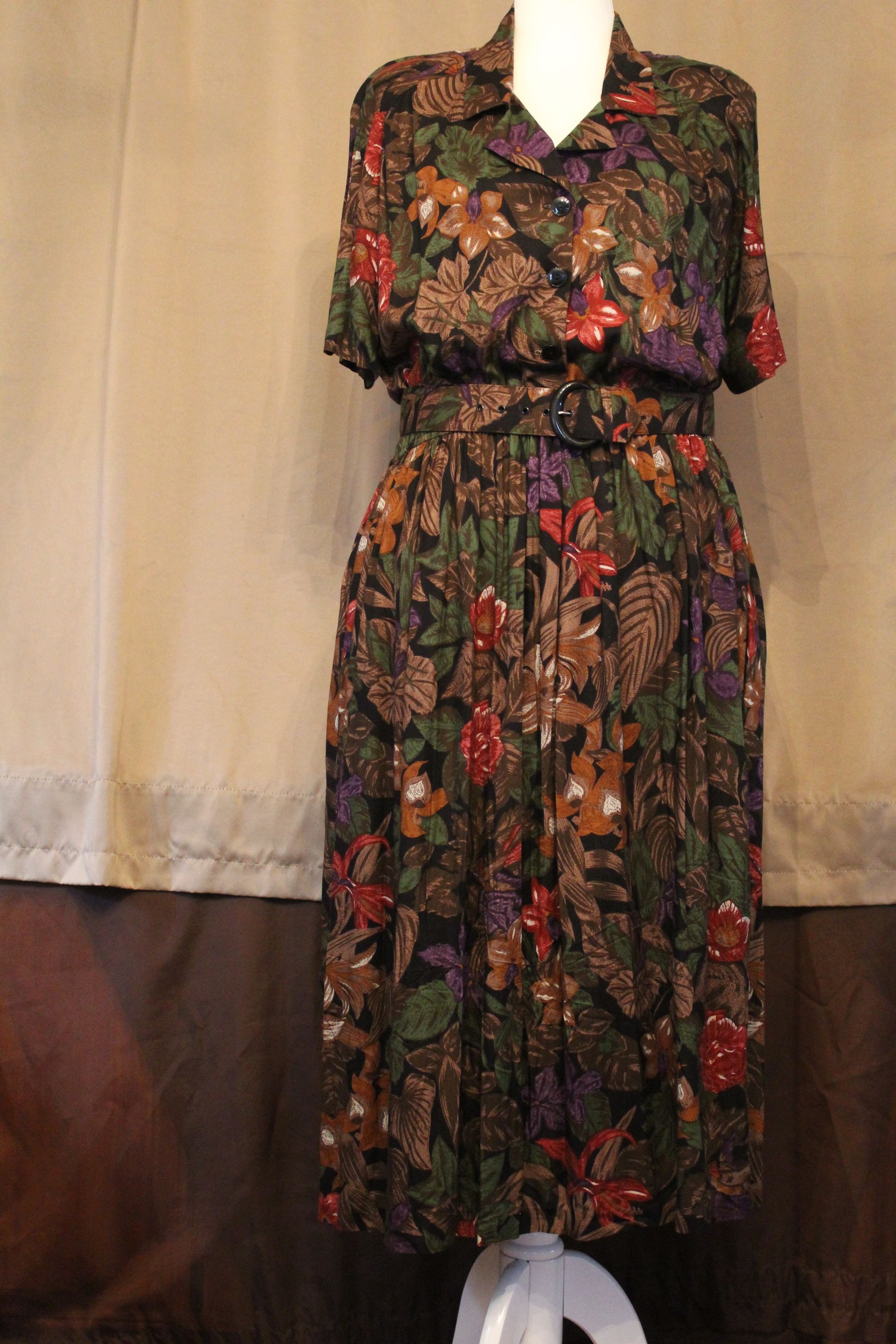 Floral-patterned black dress with short sleeves and a cinched waist on a mannequin.