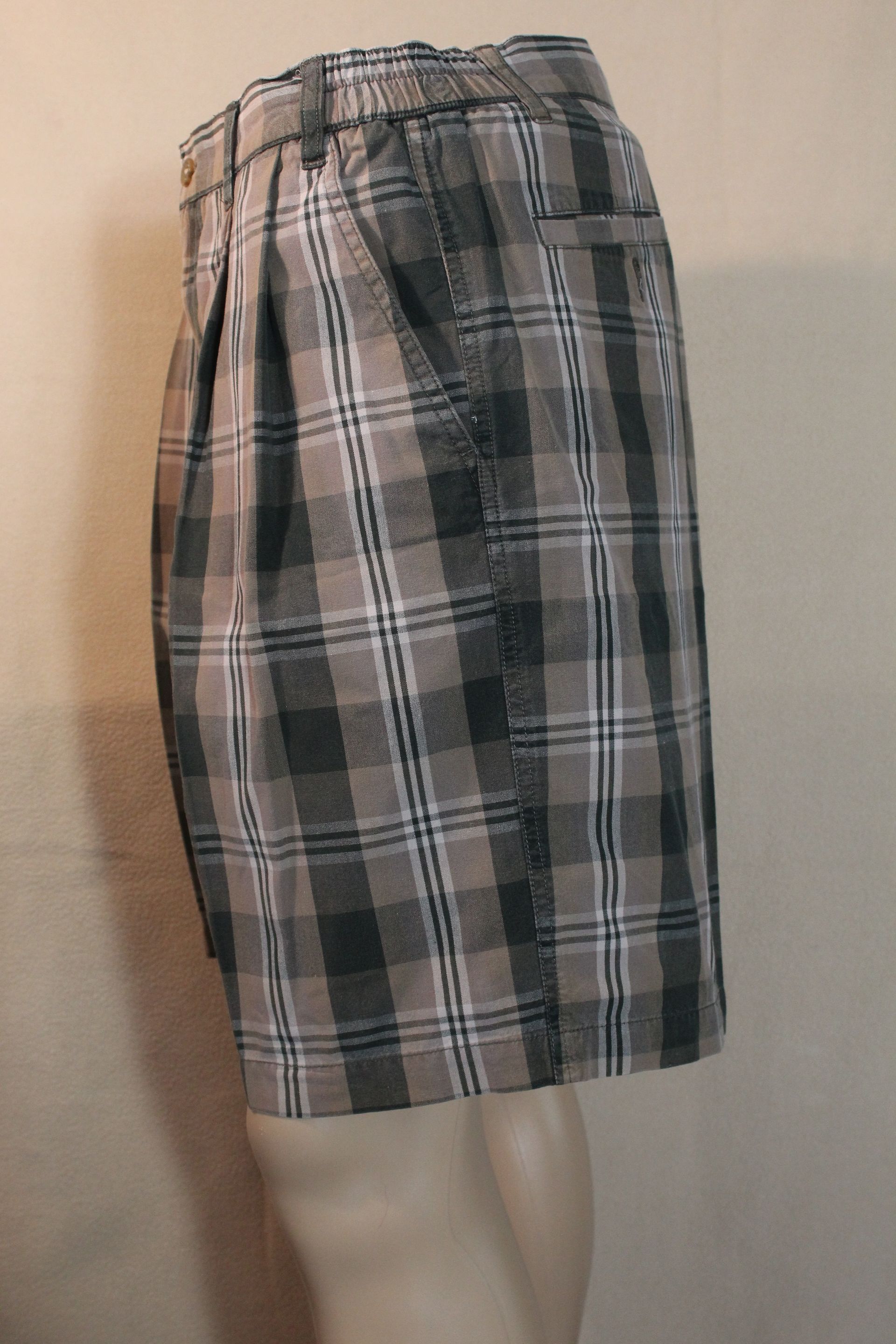 Plaid shorts on a mannequin against a plain wall.