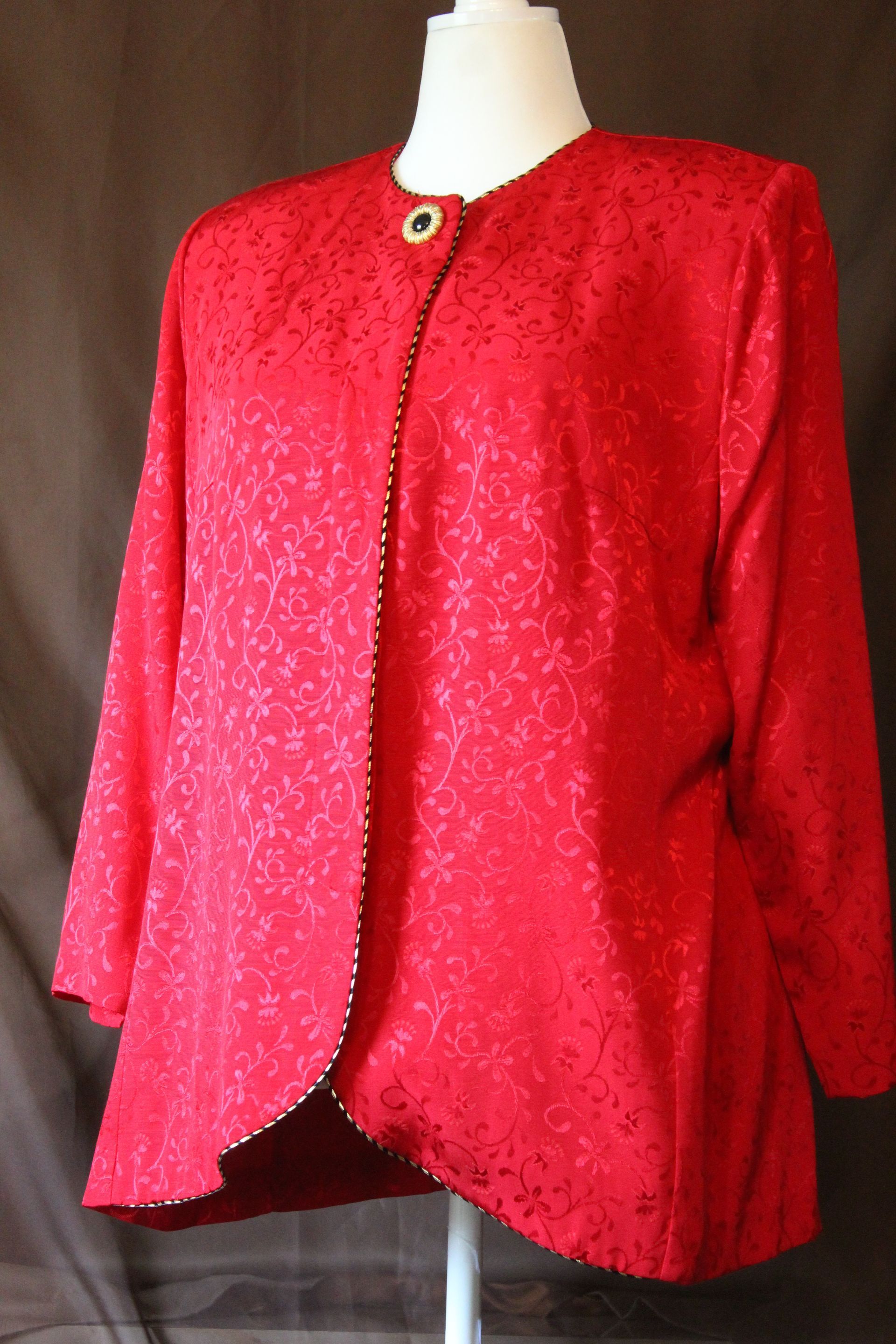 Red textured jacket with black trim on a dress form