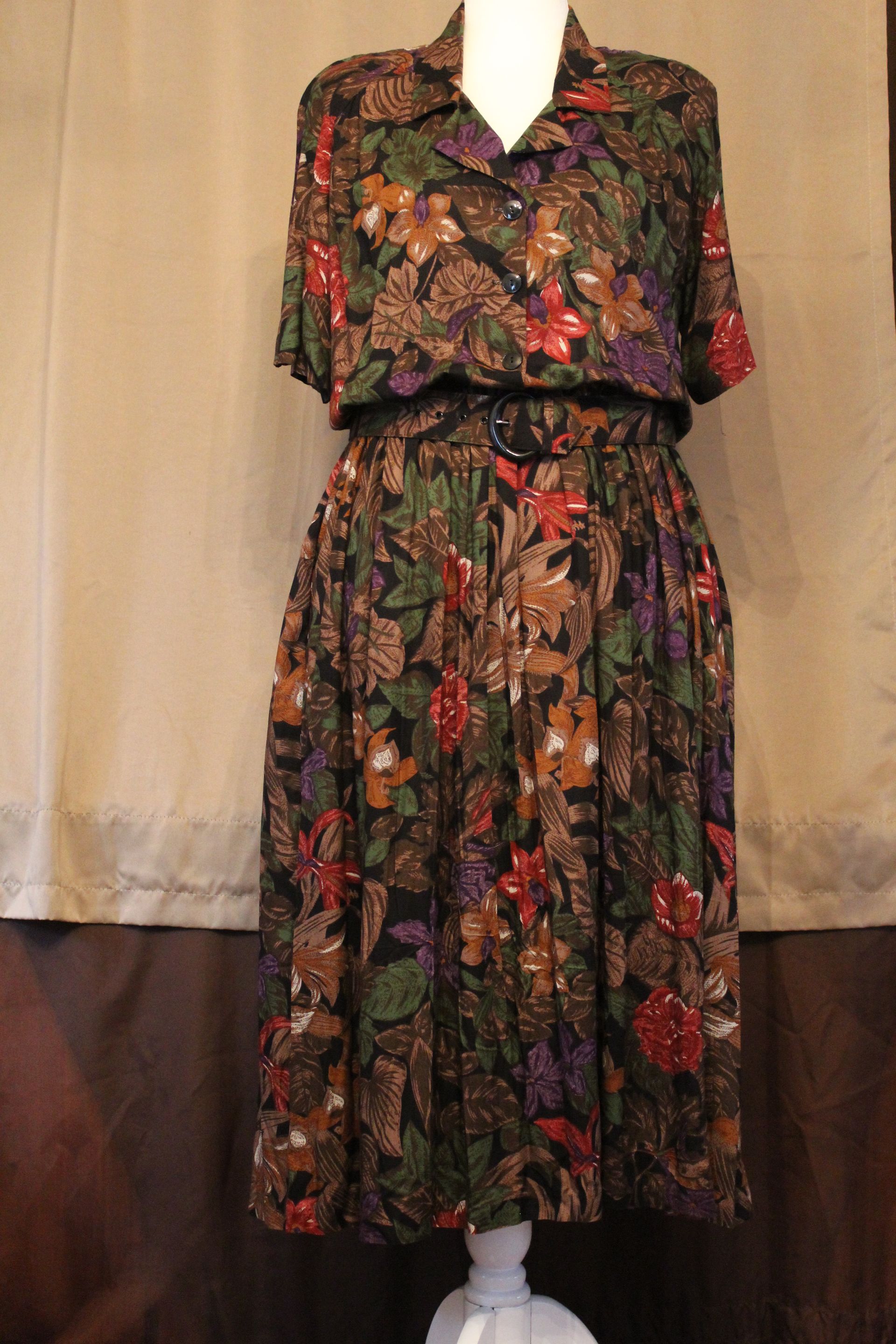 Floral-patterned black dress with short sleeves and a cinched waist on a mannequin.