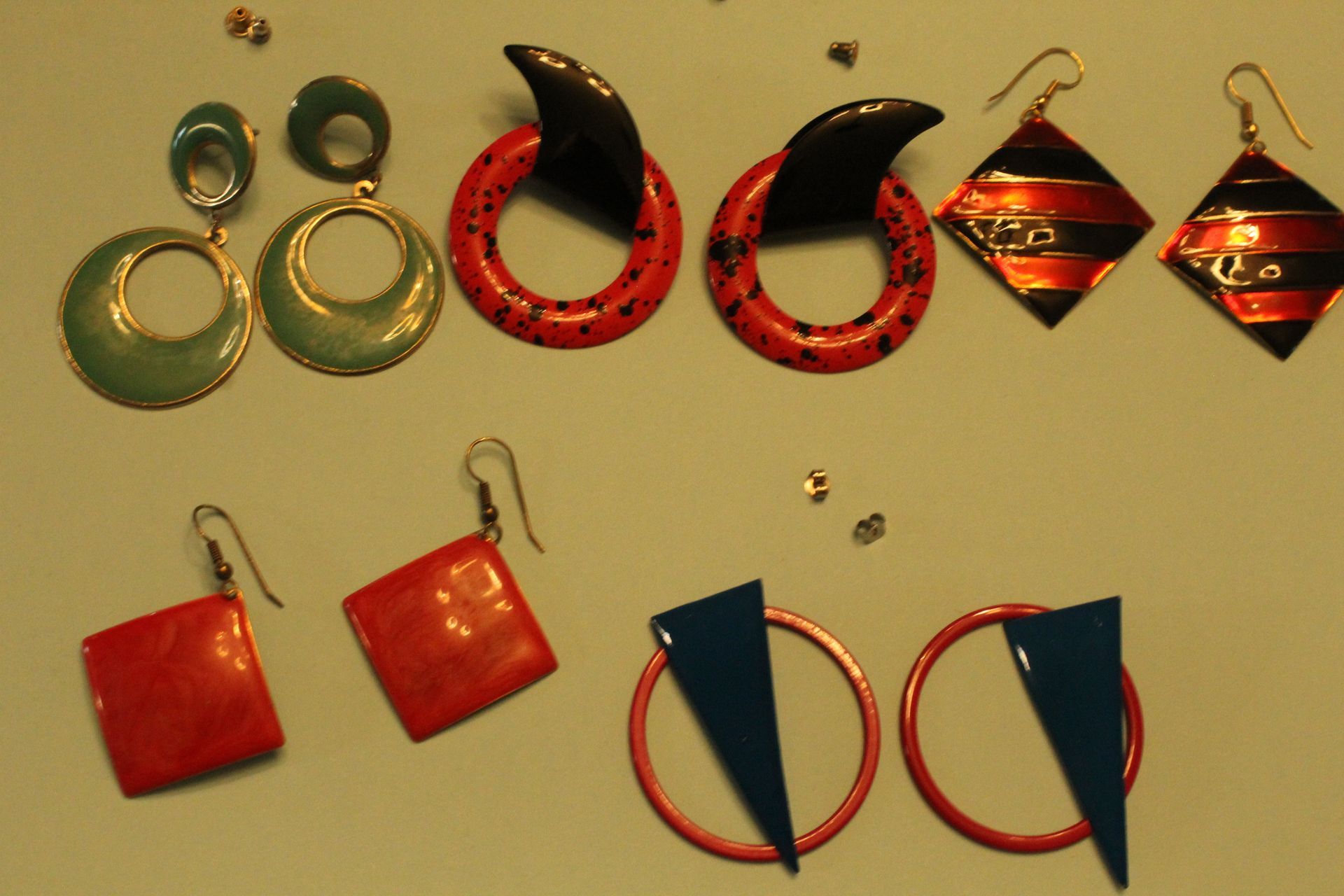 Assorted colorful earrings displayed on black cards against a beige background.