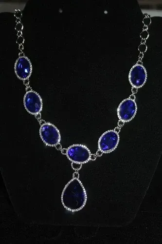 Blue teardrop gemstone pendant necklace with sparkling silver accents on a black background