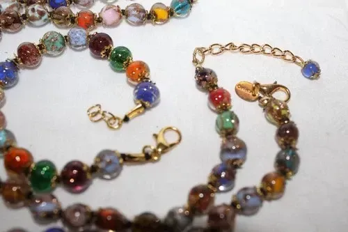 Colorful glass beads scattered in a tangled strand on a white background