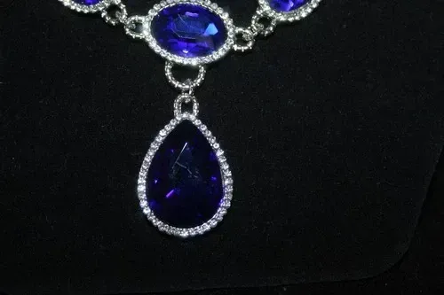 Blue teardrop gemstone pendant necklace with sparkling silver accents on a black background
