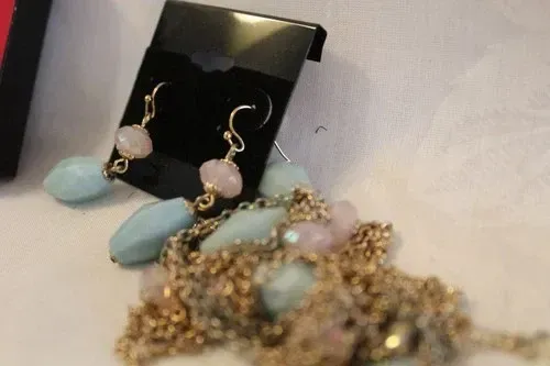 Gold and mint-green beaded necklace with matching earrings displayed on a black bust stand