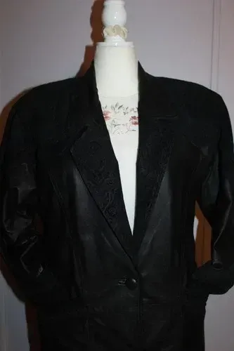 Black blazer jacket displayed on a dress form against a light background